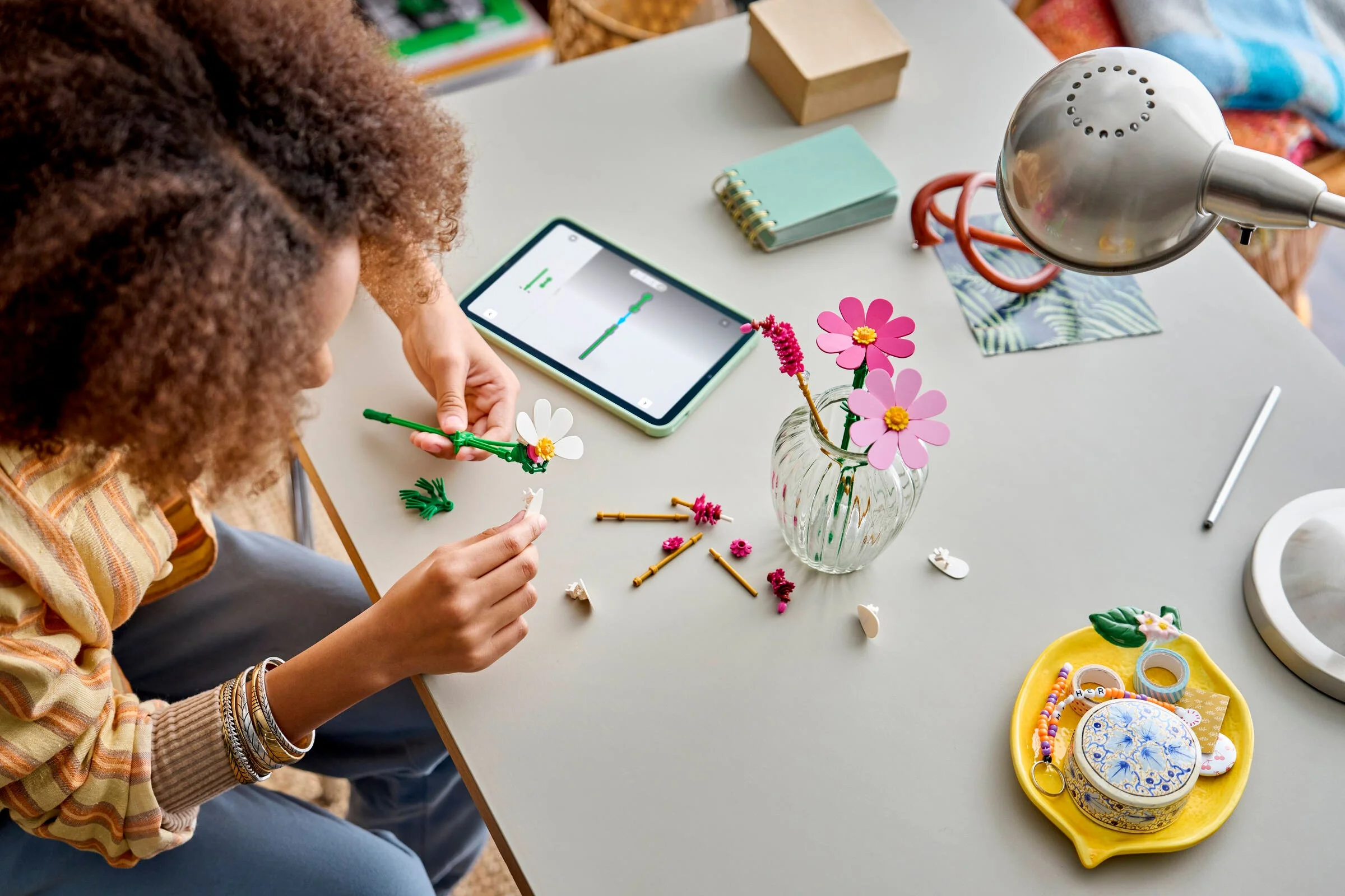 Construirea florilor Cosmos LEGO, urmând instrucțiuni pe tabletă. Flori într-o vază.
