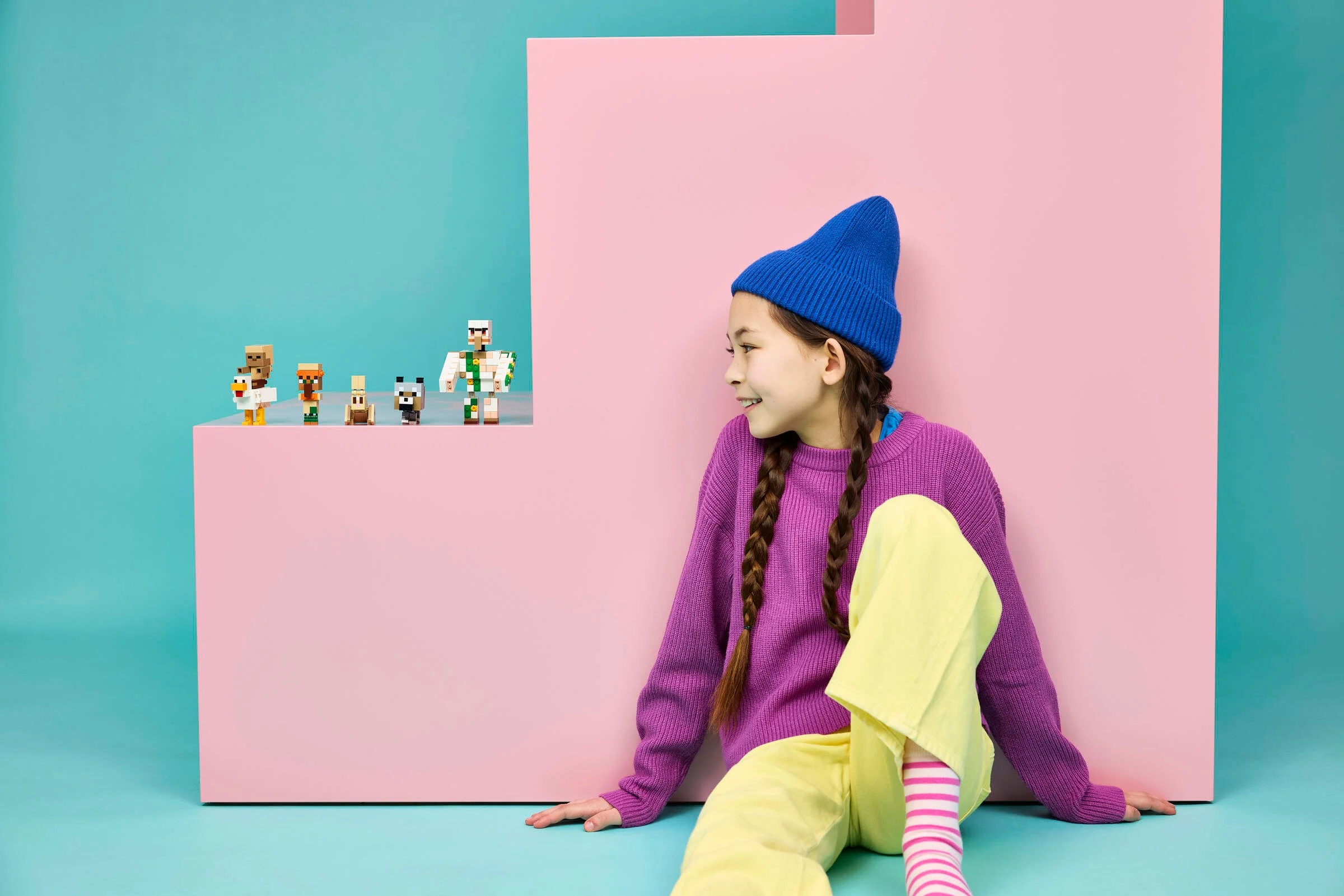 Fată zâmbind, admirând figurinele LEGO Minecraft. Concept creativ și colorat.