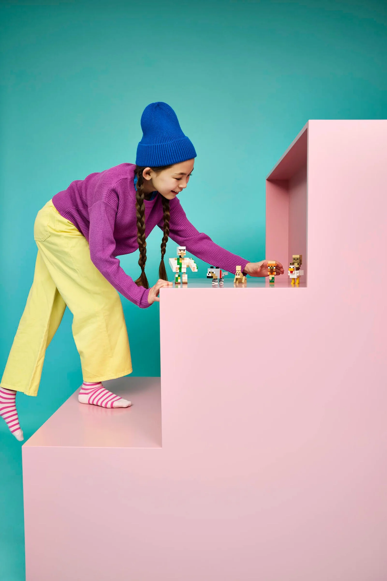 Fetiță interacționând cu minifigurine Minecraft, inclusiv un Chicken Jockey. Joacă și creativitate.