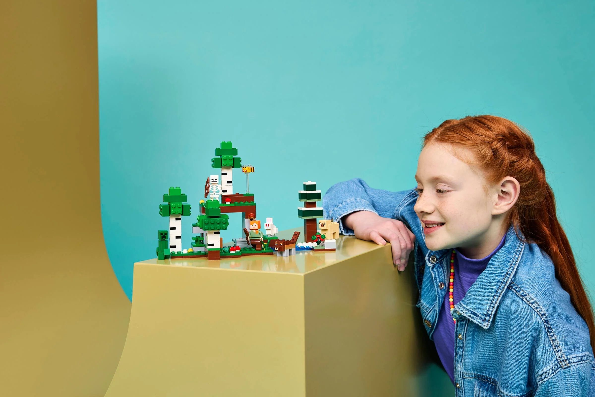 Fetiță admirând setul LEGO Minecraft Aventura Primei Nopți. Set detaliat, plin de creaturi Minecraft.