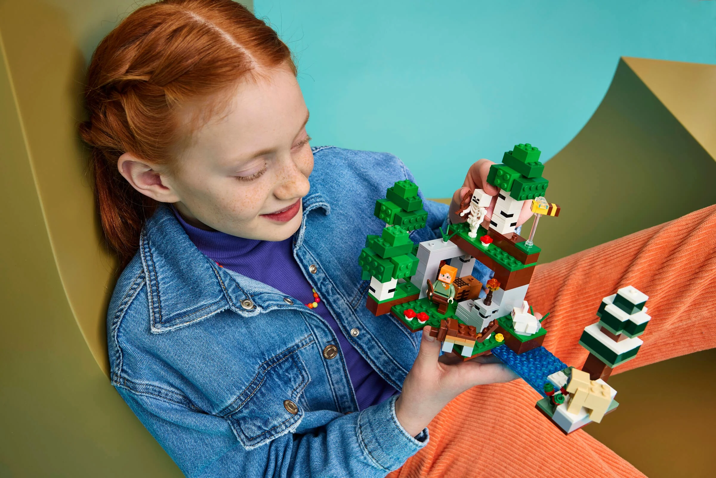 Fetiță admirând setul LEGO Minecraft 21593, „Prima aventură nocturnă”.
