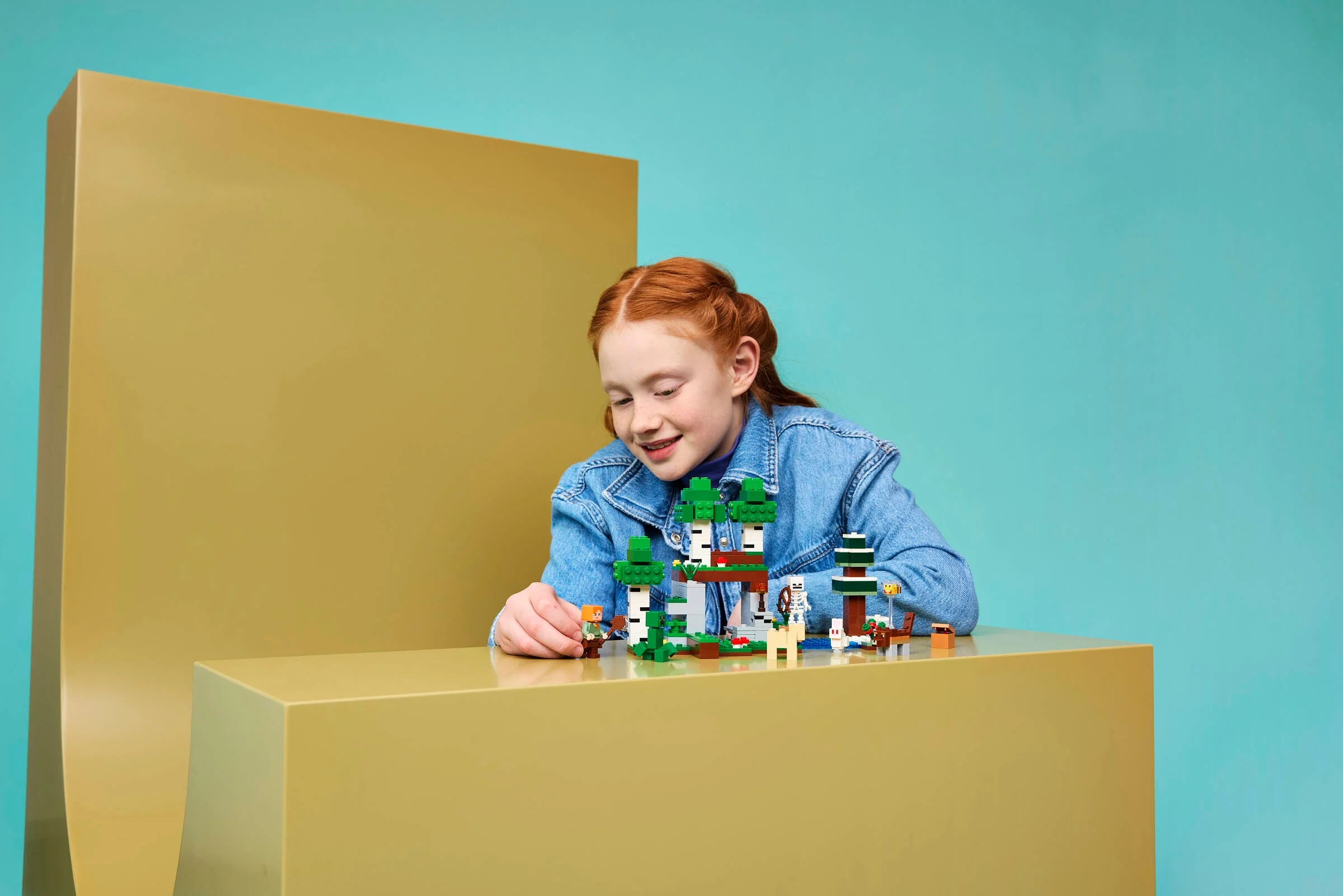 Fetiță se joacă cu setul LEGO Minecraft Prima Aventură, zâmbind.