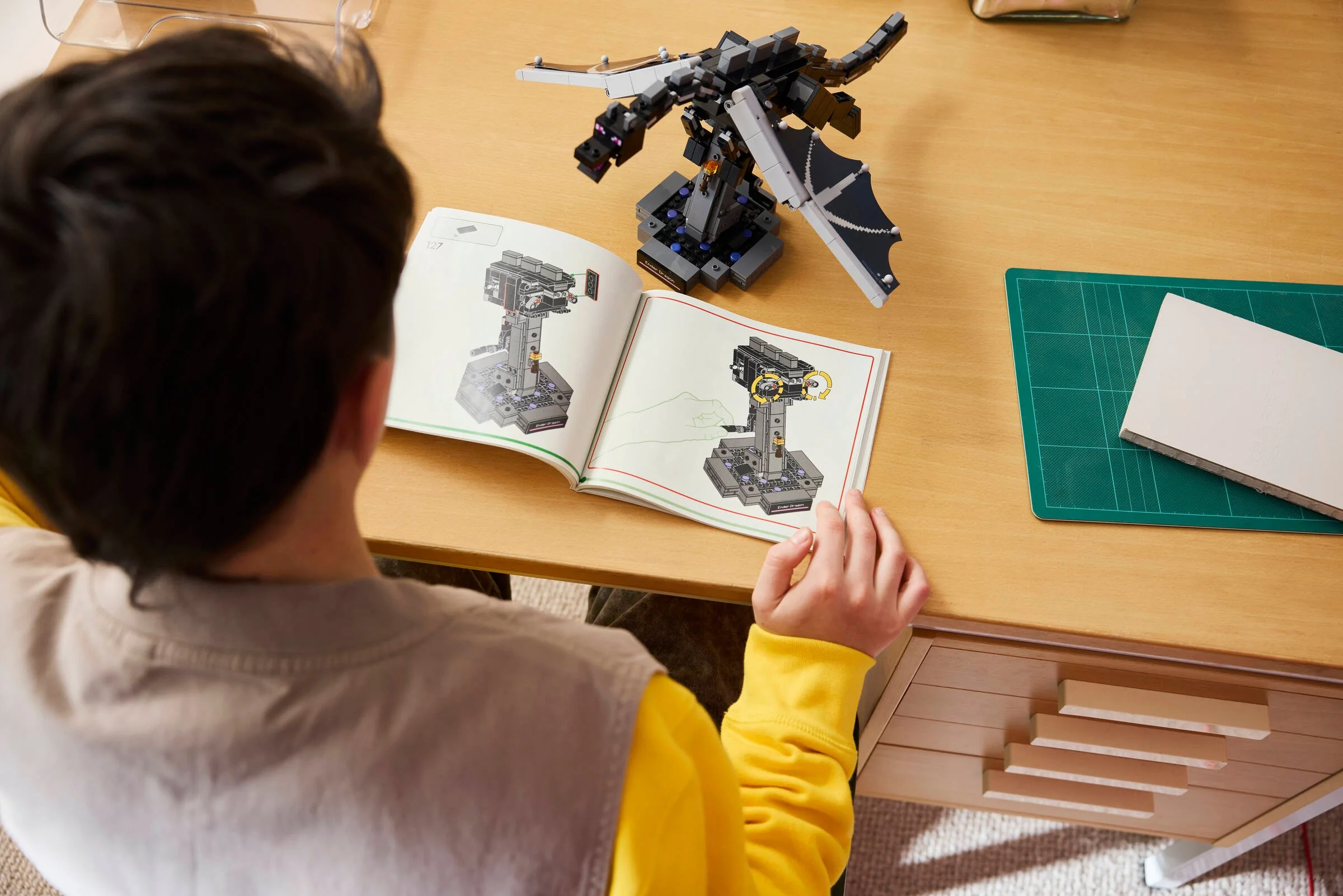 Un copil construiește Ender Dragon folosind instrucțiunile LEGO. Set detaliat, captivant.