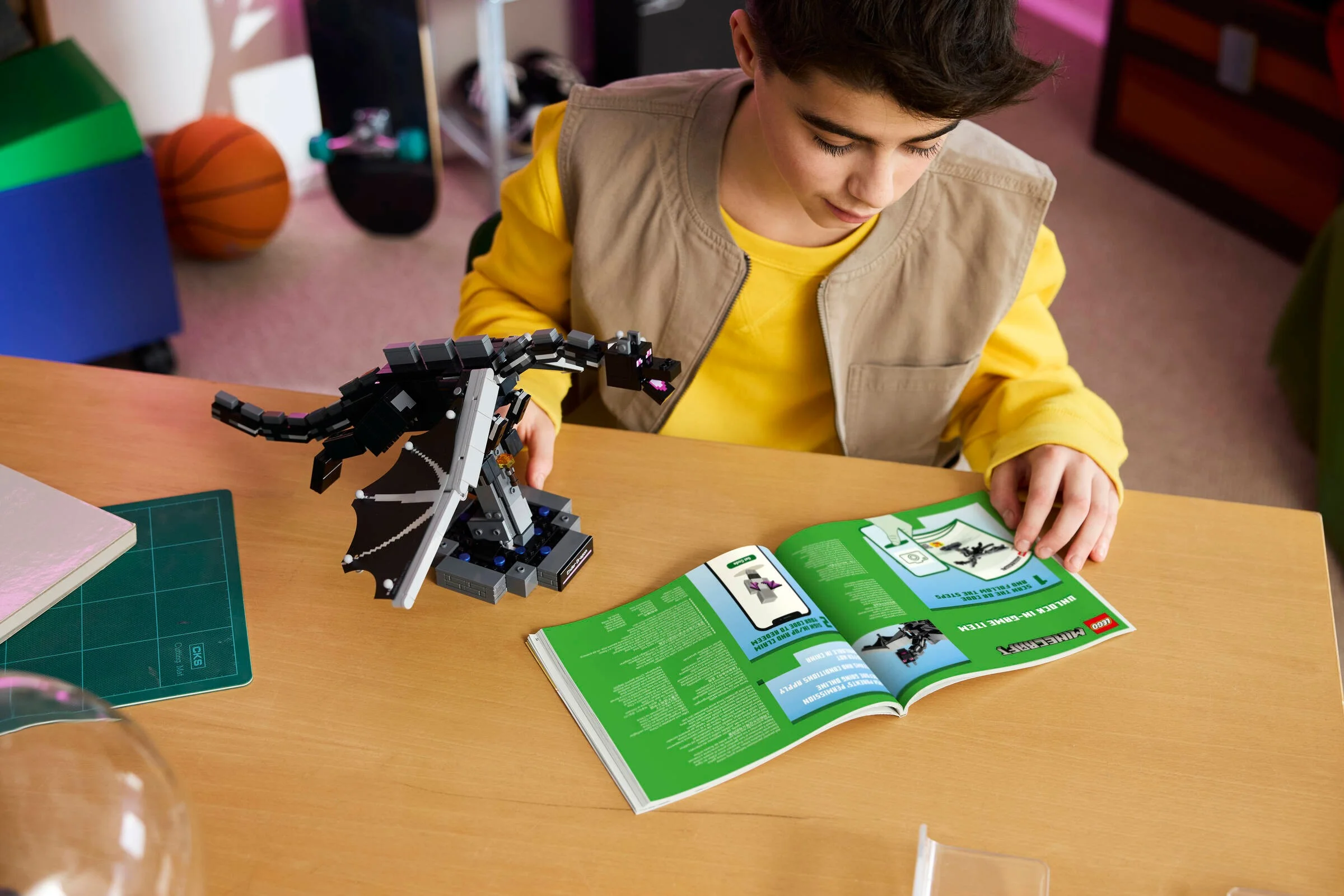 Copil construind Ender Dragon LEGO Minecraft, urmând instrucțiunile din broșură.
