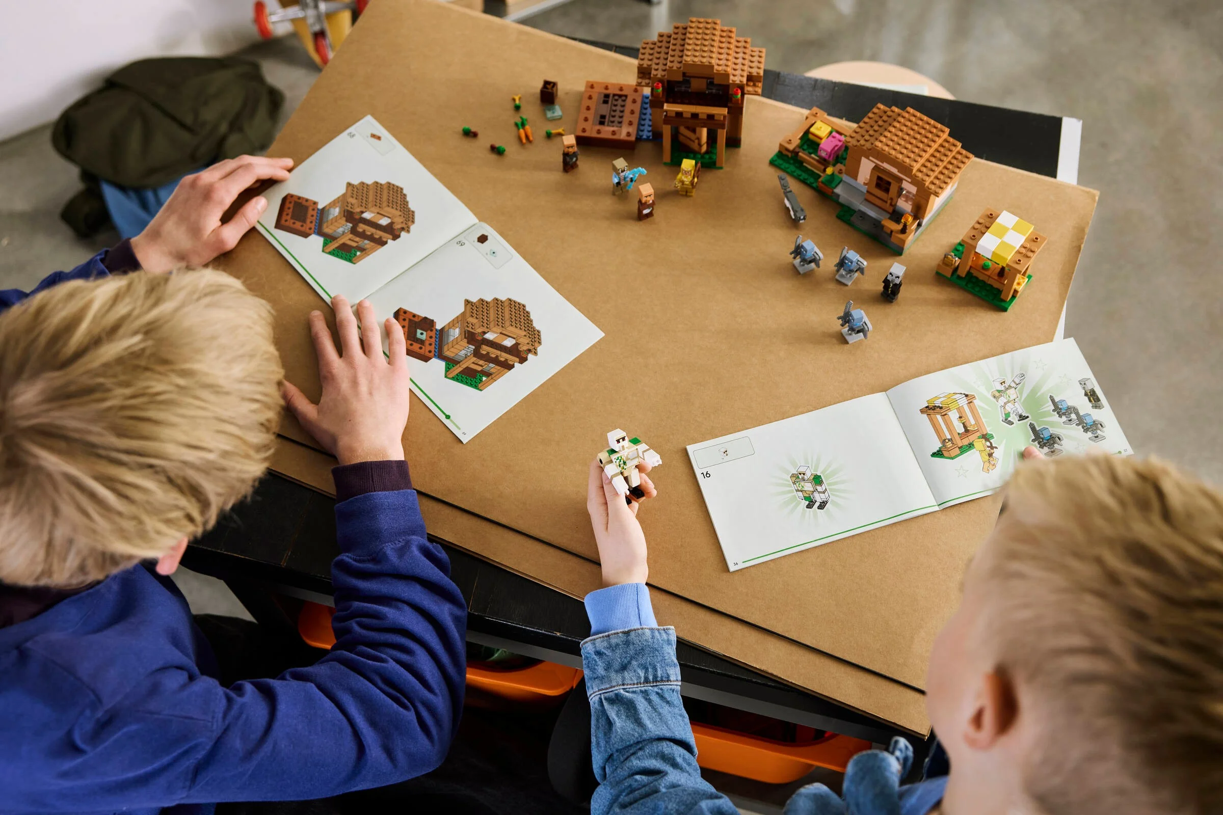 Copii construind setul LEGO Minecraft 21596. Instrucțiuni deschise, piese împrăștiate pe masă.