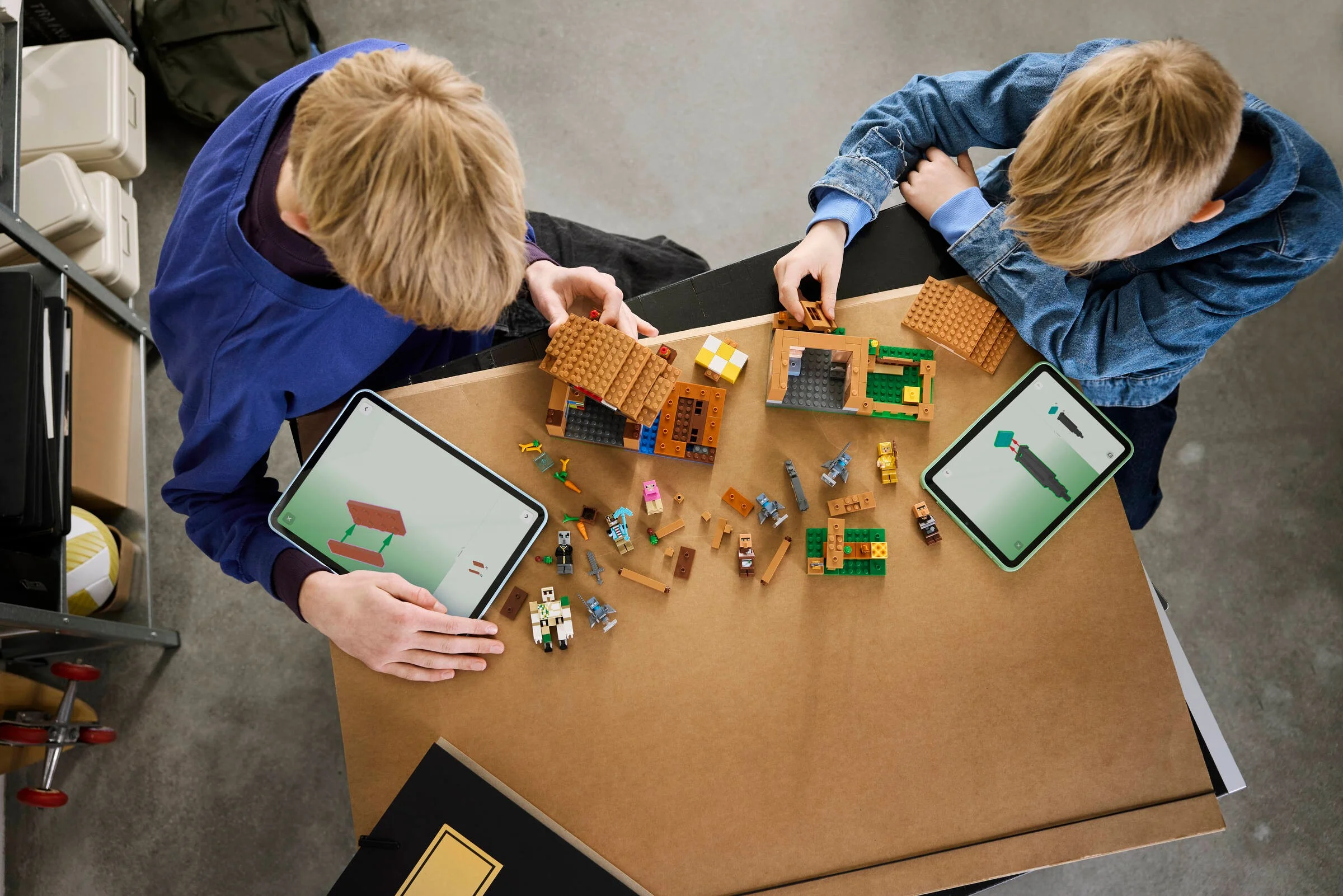Doi copii construiesc setul LEGO Minecraft 21596, folosind tablete pentru instrucțiuni.