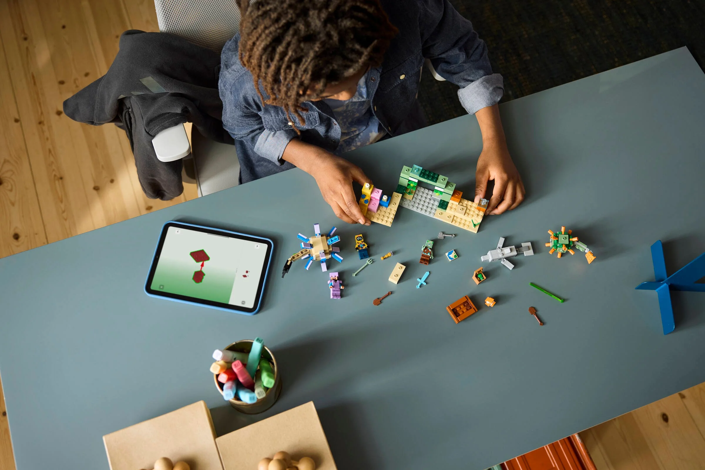 Copil construind setul LEGO Minecraft Underwater Adventure. Instrucțiuni pe tabletă.