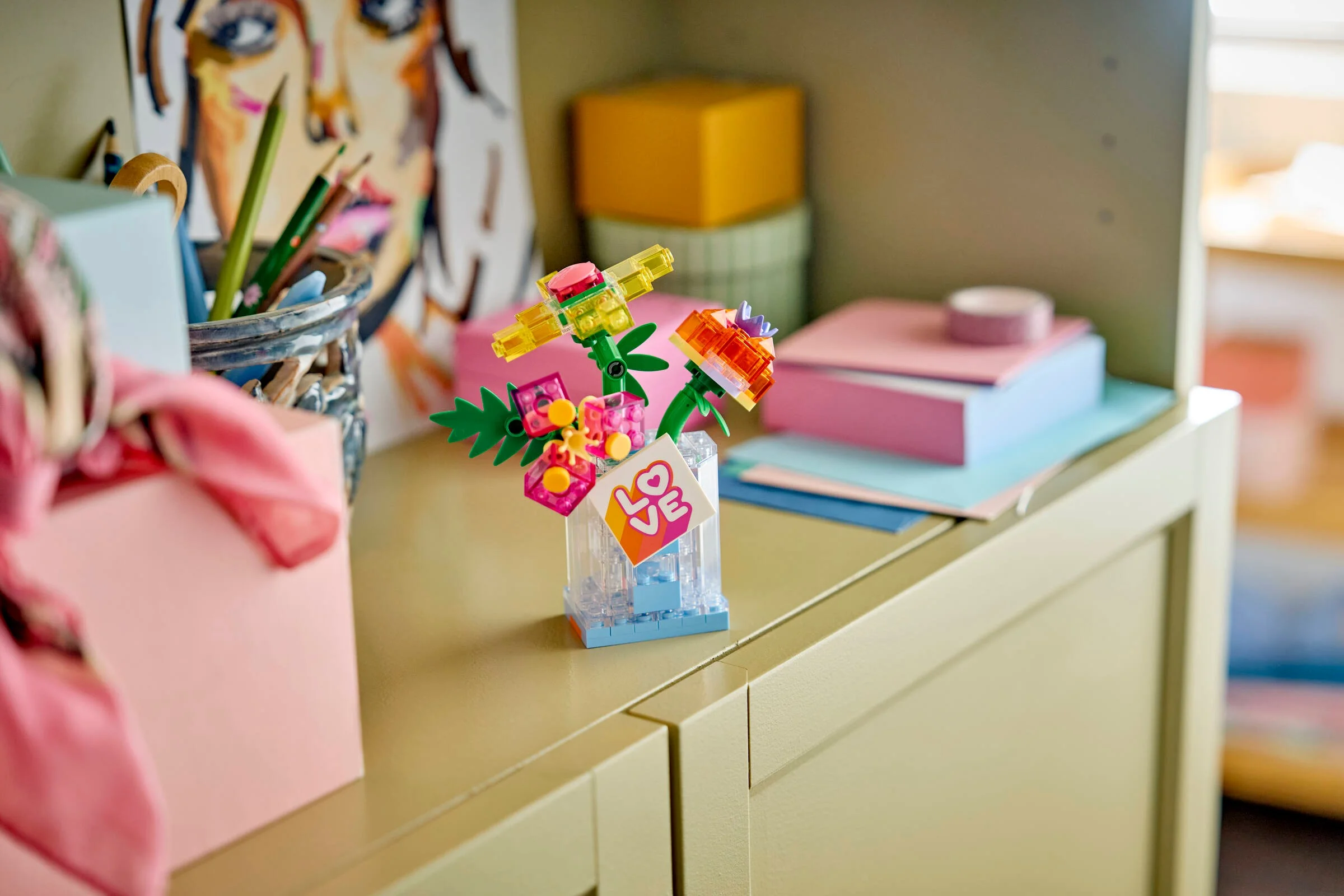 Aranjament floral LEGO viu colorat într-o vază transparentă, decor pe un dulap. O alegere creativă.