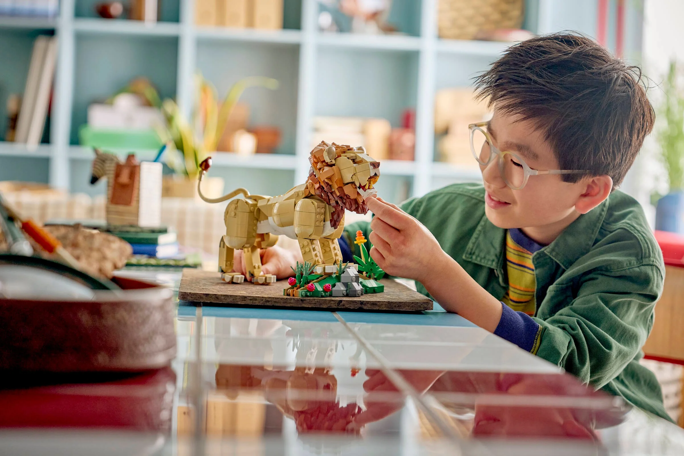 Un băiat admiră un leu LEGO Creator. Model detaliat, expresiv și prietenos.