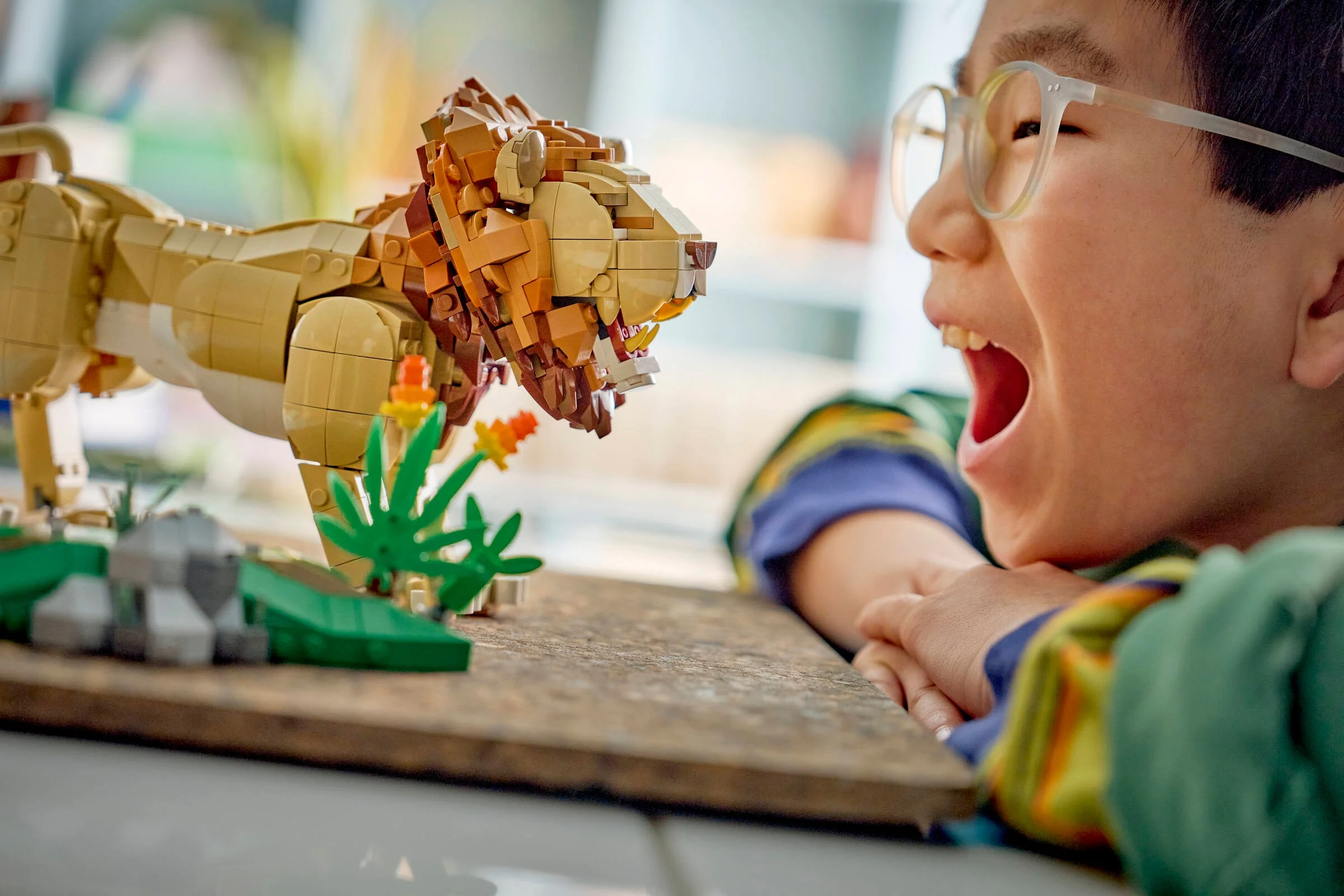 Un băiat entuziasmat se uită la un leu LEGO. O jucărie captivantă!
