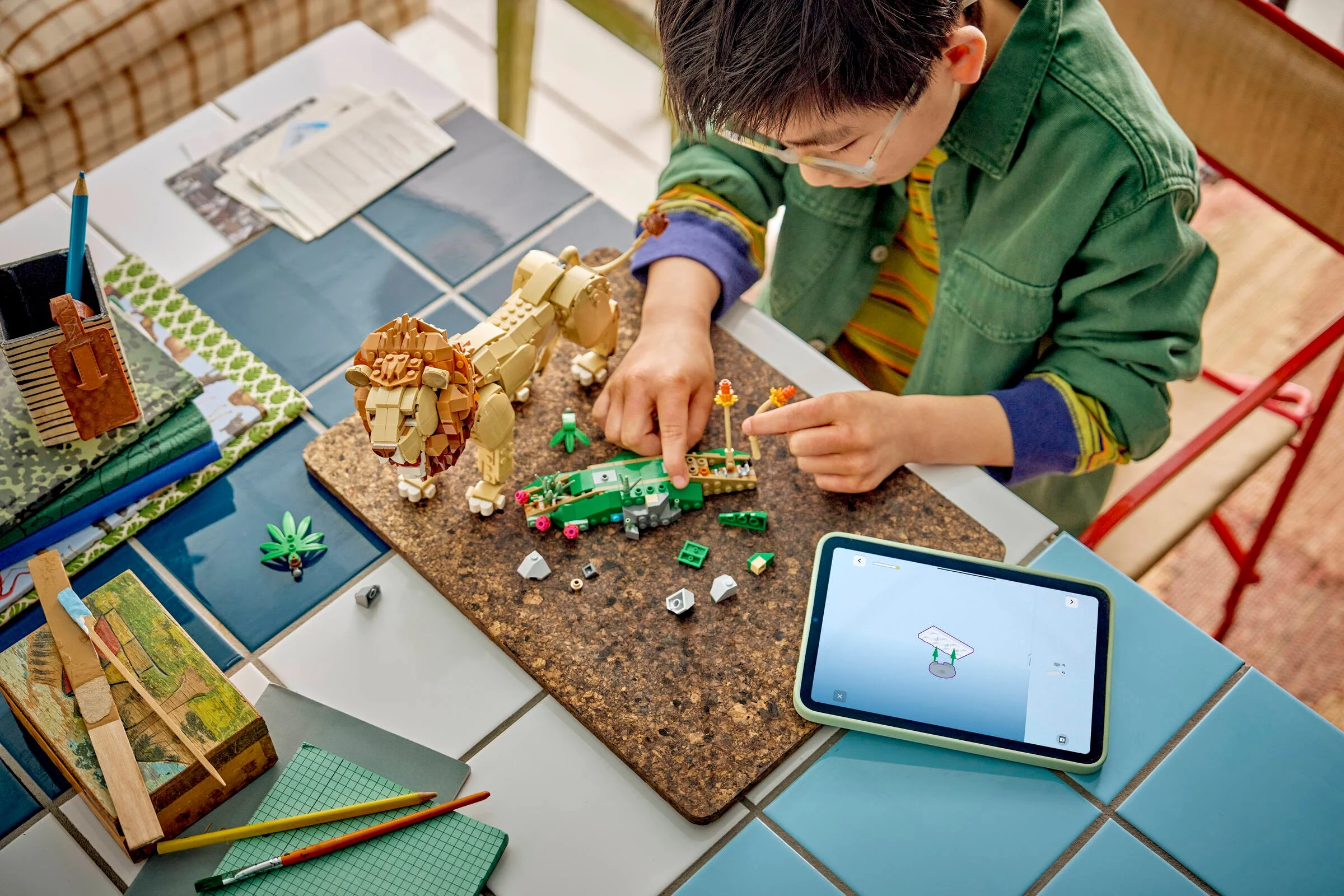 Copil construind setul LEGO 31386: Leu măreț și dioramă cu instrucțiuni digitale.