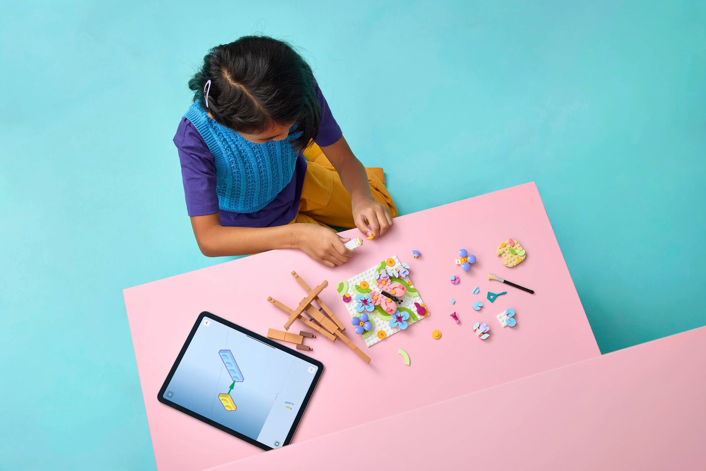 O fată construiește setul LEGO Floral Art Painting, folosind instrucțiuni digitale pe tabletă.