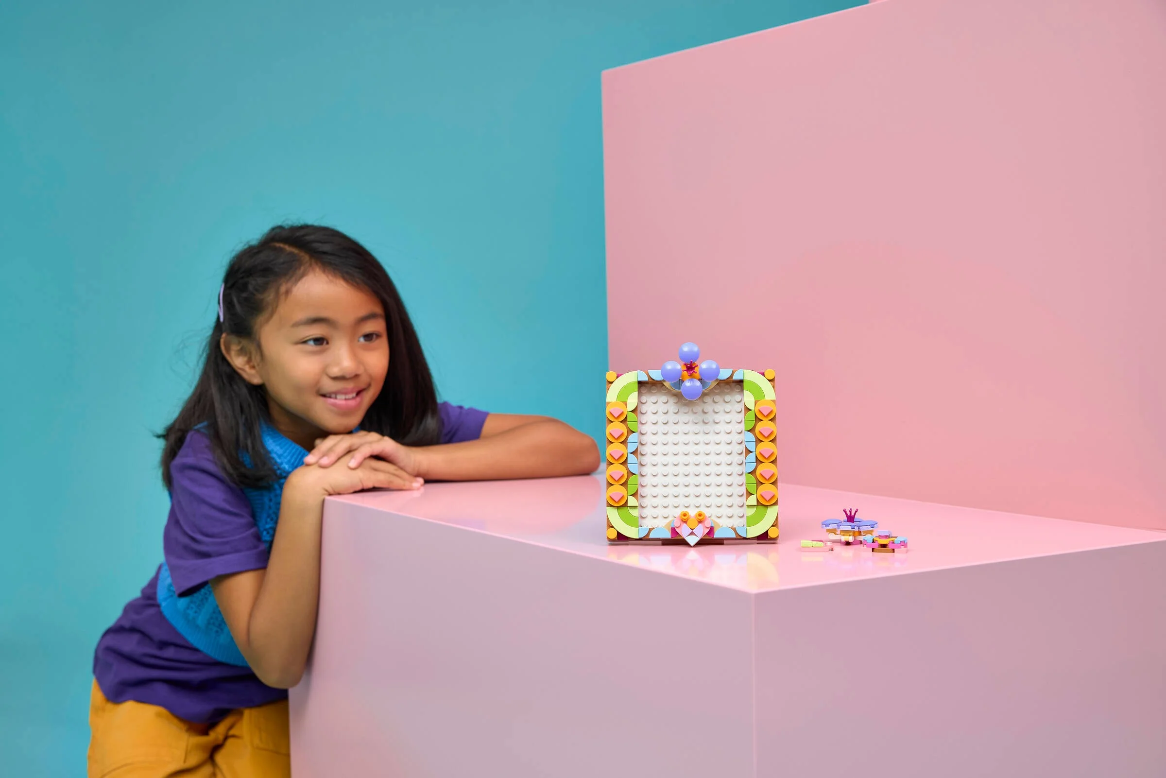 O fetiță zâmbește lângă modelul LEGO Floral Art Painting, set 31390.