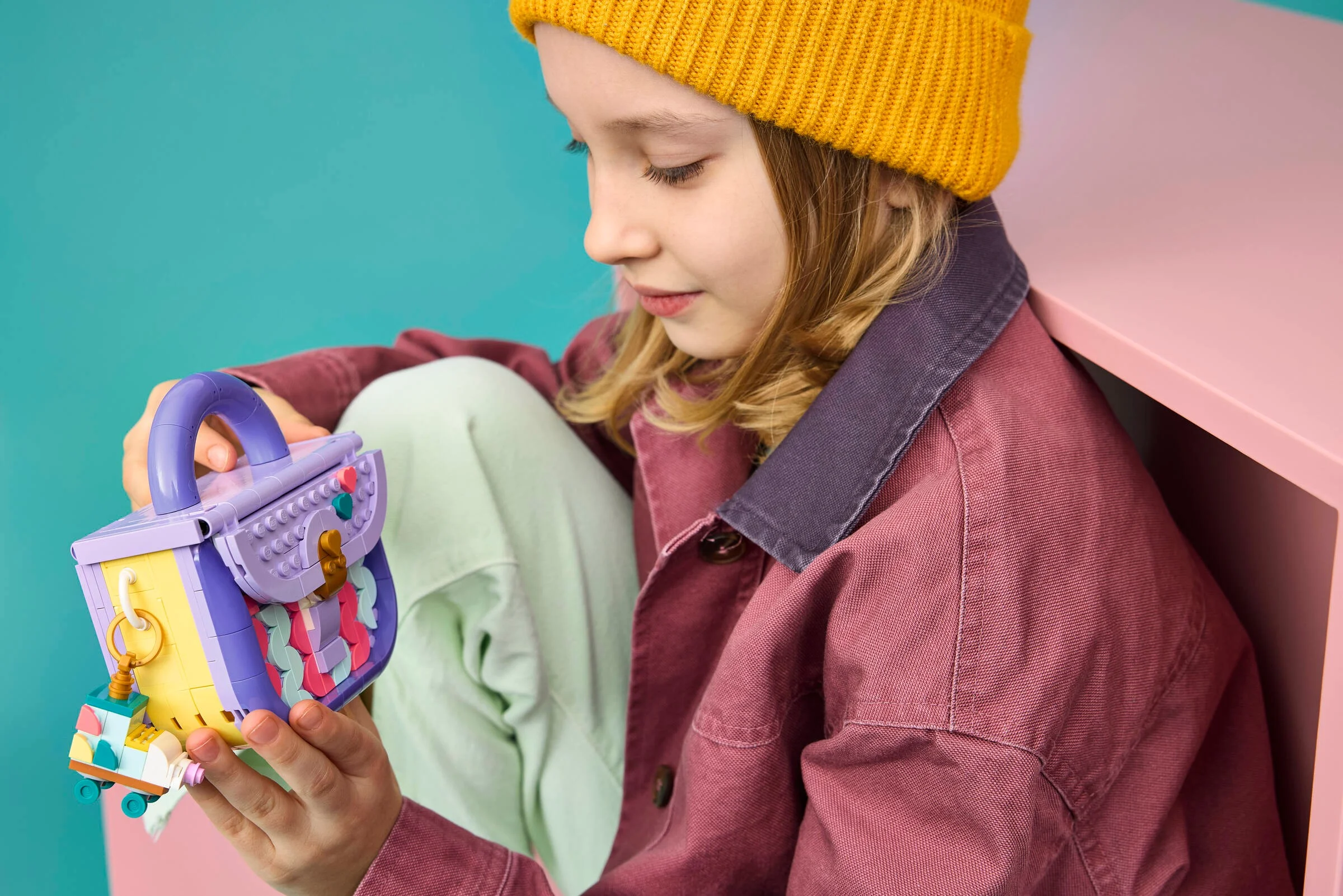 Fată admirând geanta LEGO Fashion Bag, detaliu viu al modelului.