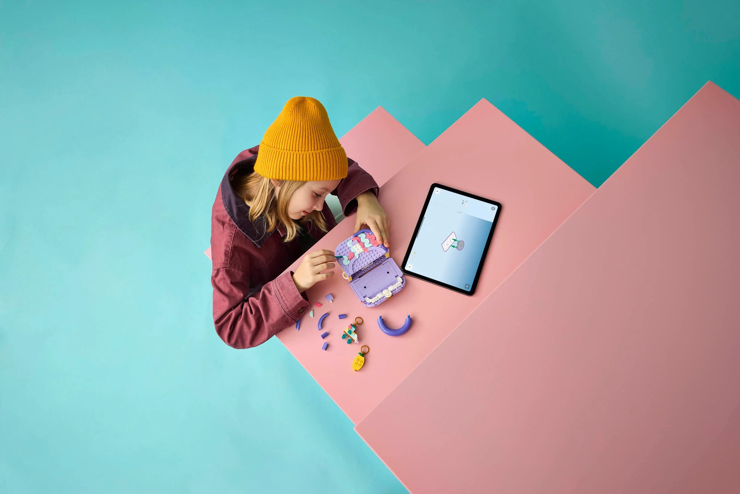 Fată construind setul LEGO geantă, urmând instrucțiuni digitale pe tabletă. Vesel!
