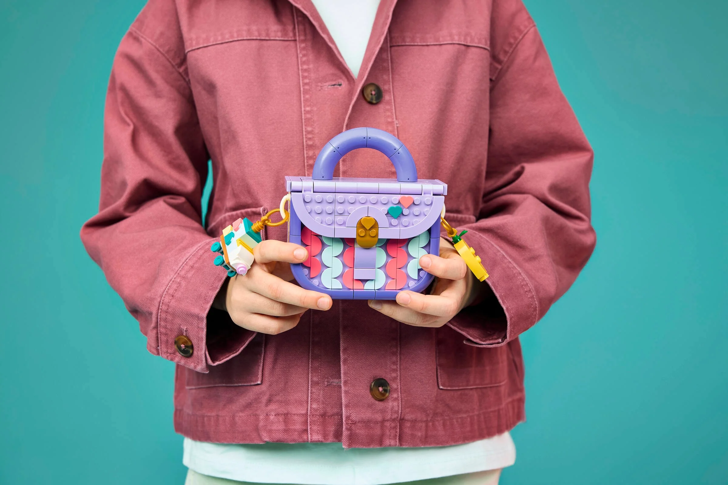 Geanta LEGO finită, ținută de o persoană cu jachetă roz. Aspect modern și distractiv.