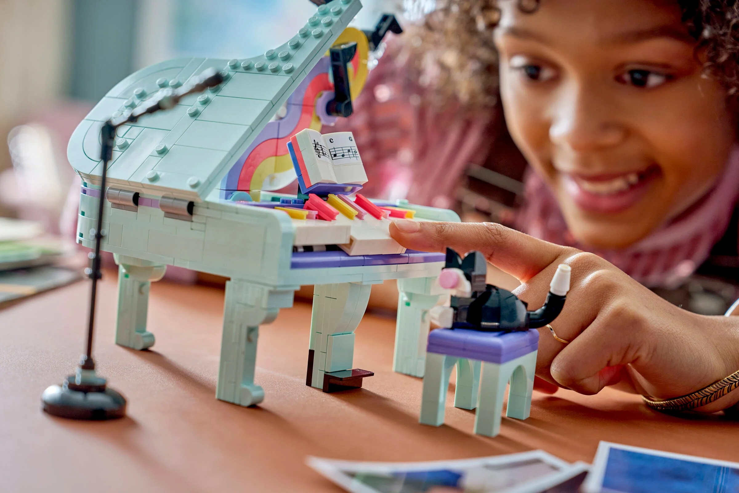 Prim-plan cu pianul LEGO Creator 31392 și o fată zâmbitoare care se joacă.