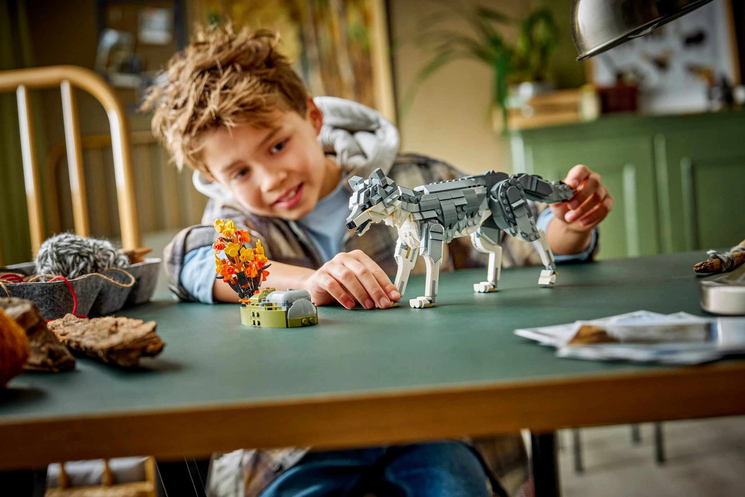 Băiat se joacă cu lupul LEGO și un decor de tufiș tomnatic. Activitate creativă și distractivă.