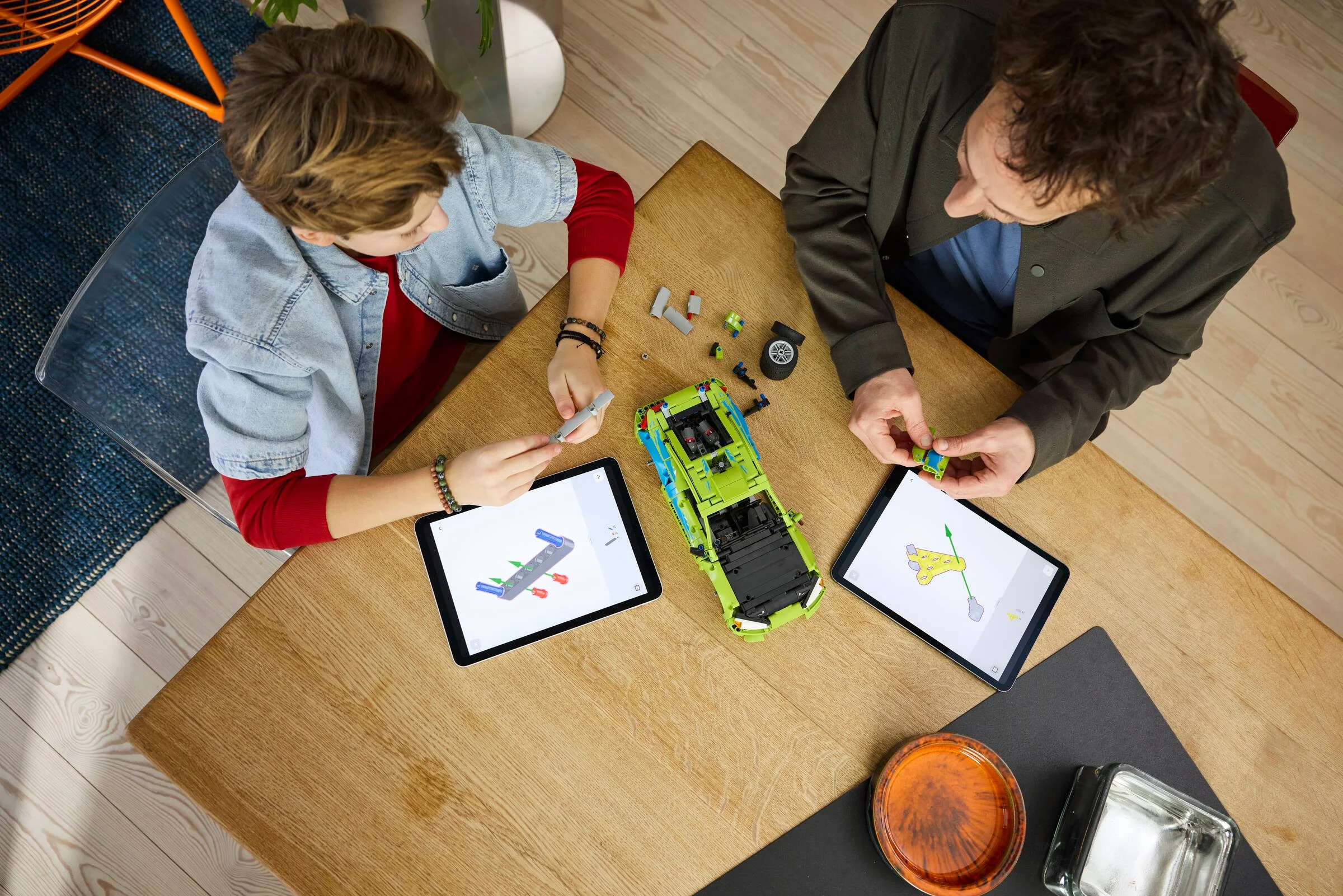 Copil și adult construind împreună modelul LEGO Mitsubishi Eclipse, folosind instrucțiuni digitale.