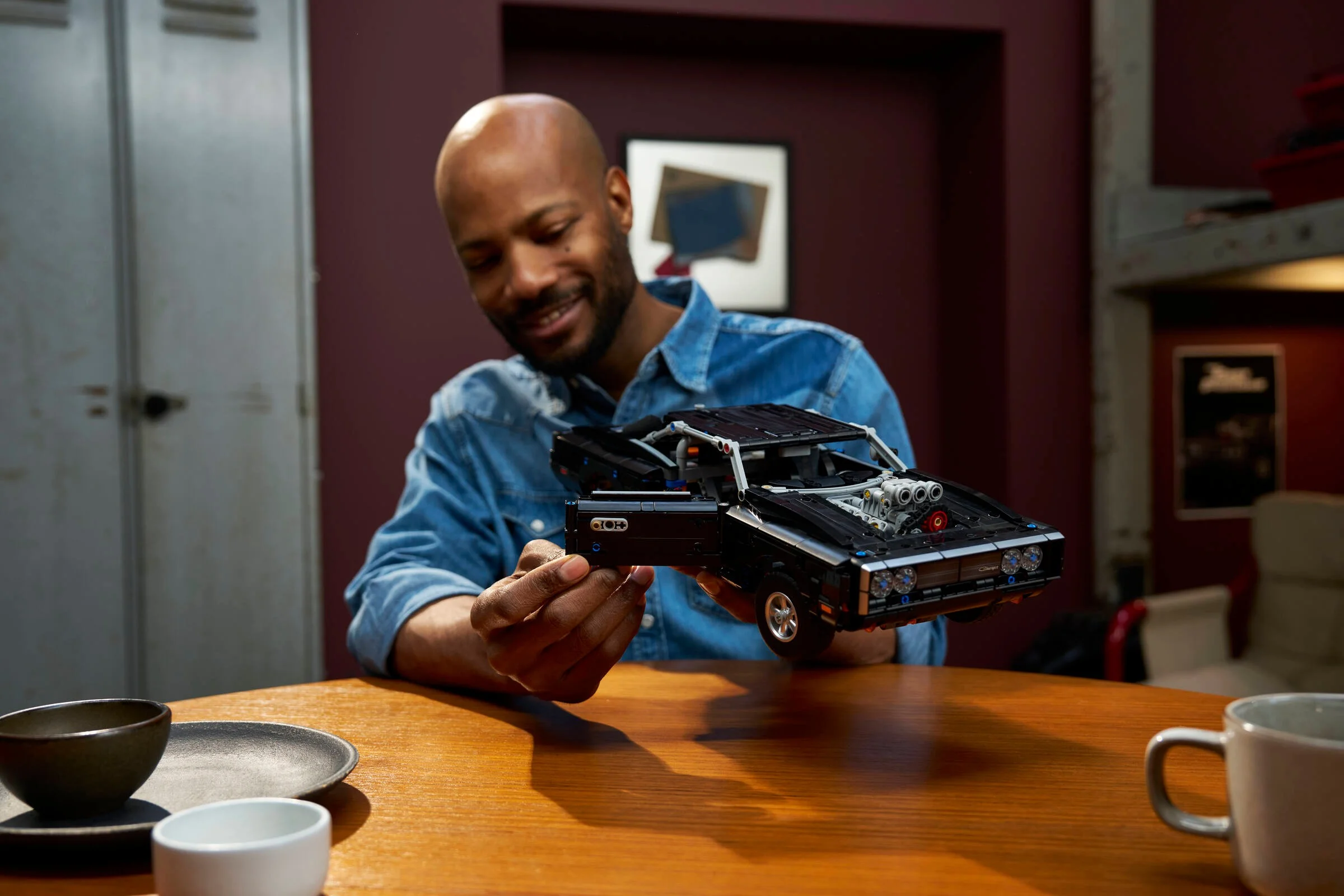 Un bărbat zâmbește ținând modelul Dodge Charger R/T în mână, într-un cadru ambientat.