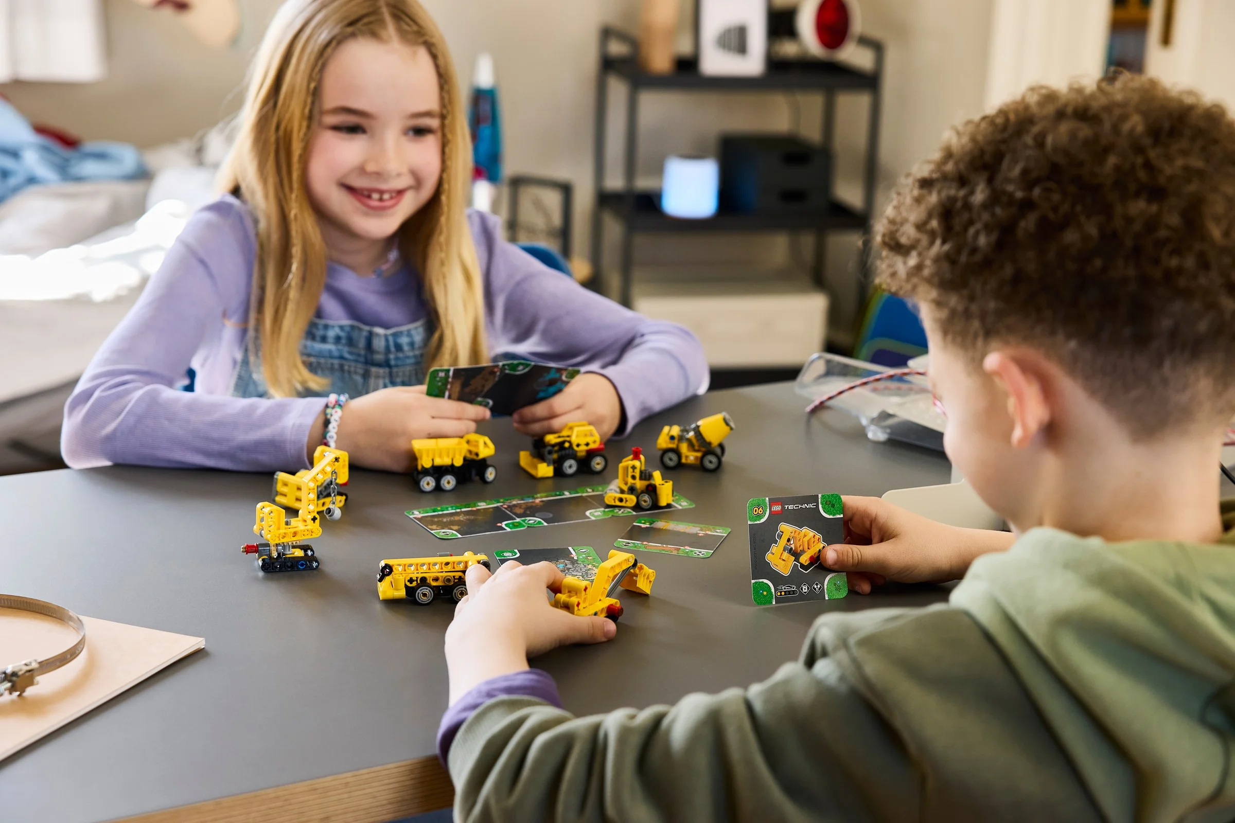 Copii se joacă cu mini-modele LEGO Technic, cu cărți de instrucțiuni. Distracție cu vehicule de construcții.