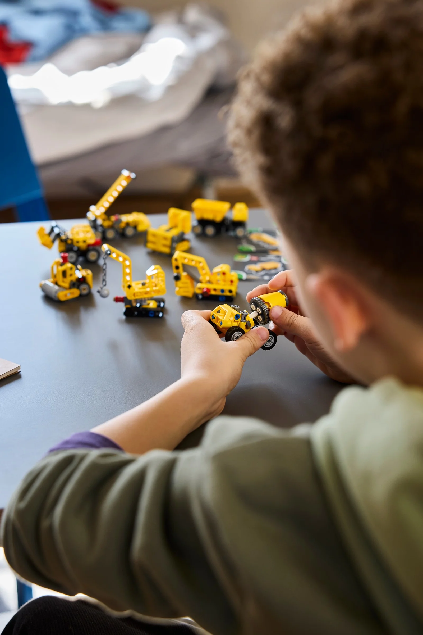Un copil construiește modele LEGO Technic galbene, detalii fine ale construcțiilor și joacă.