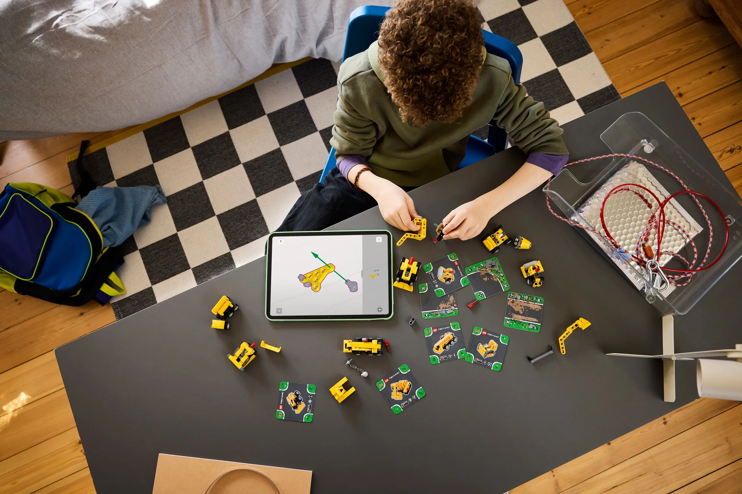 Copil construind modelul Road Roller 42233 folosind instrucțiuni digitale pe tabletă.