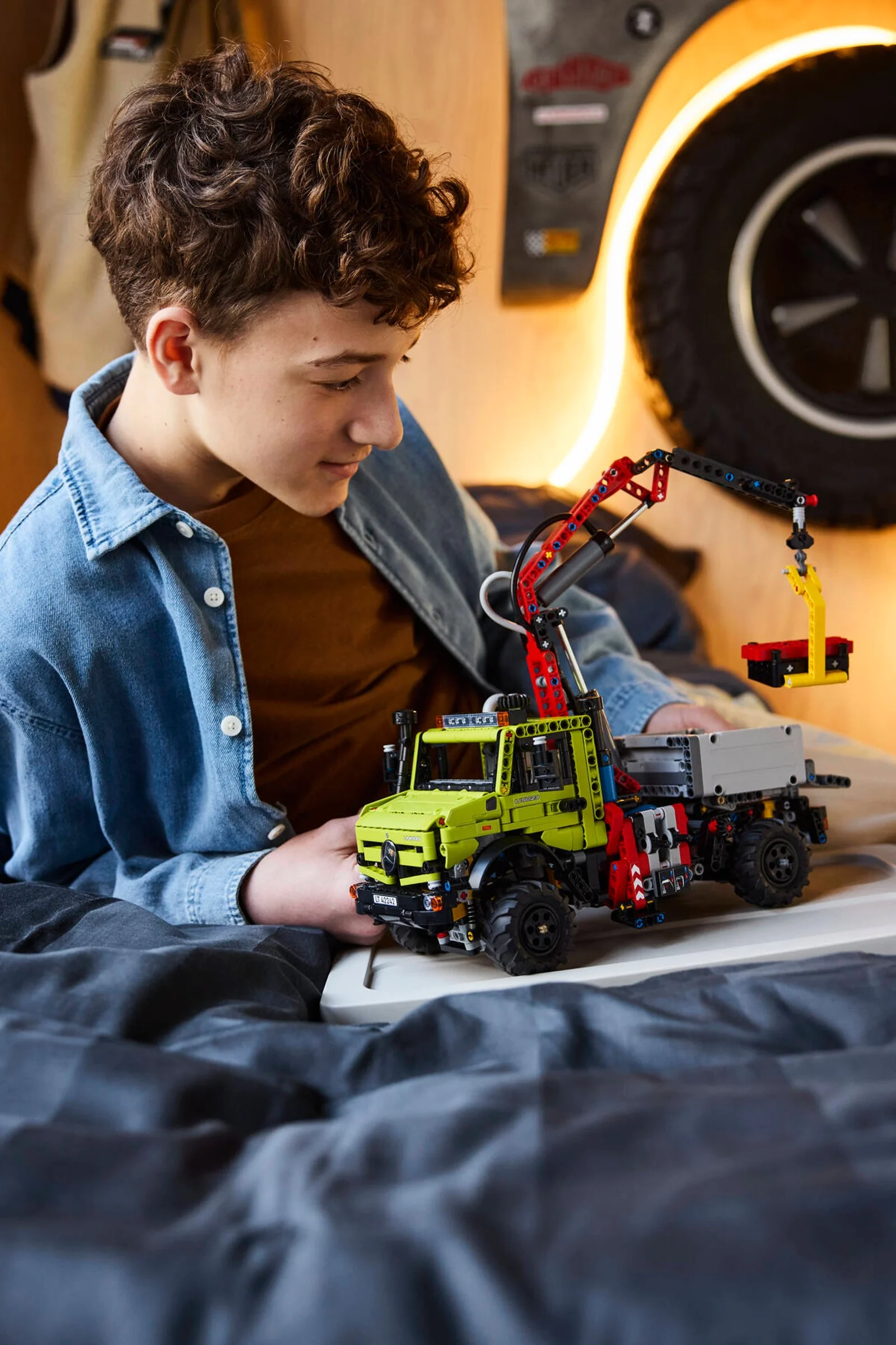 Un băiat se joacă cu modelul LEGO Mercedes-Benz Unimog U 5023 cu macara.