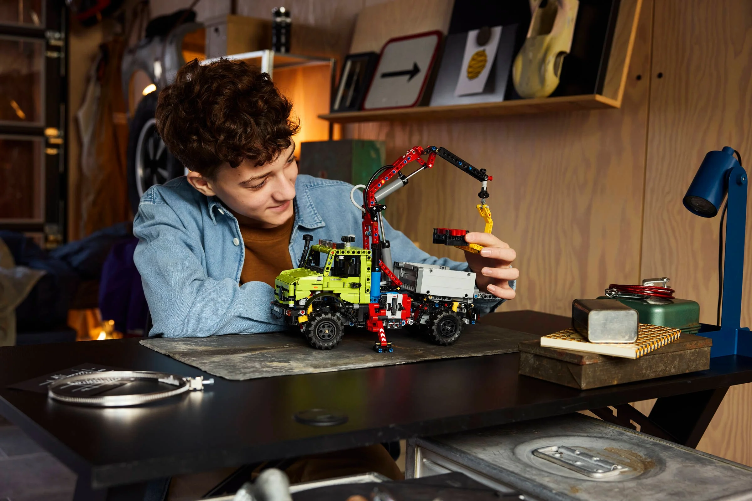 Un băiat manevrează cu atenție brațul macaralei Unimog-ului LEGO Technic.