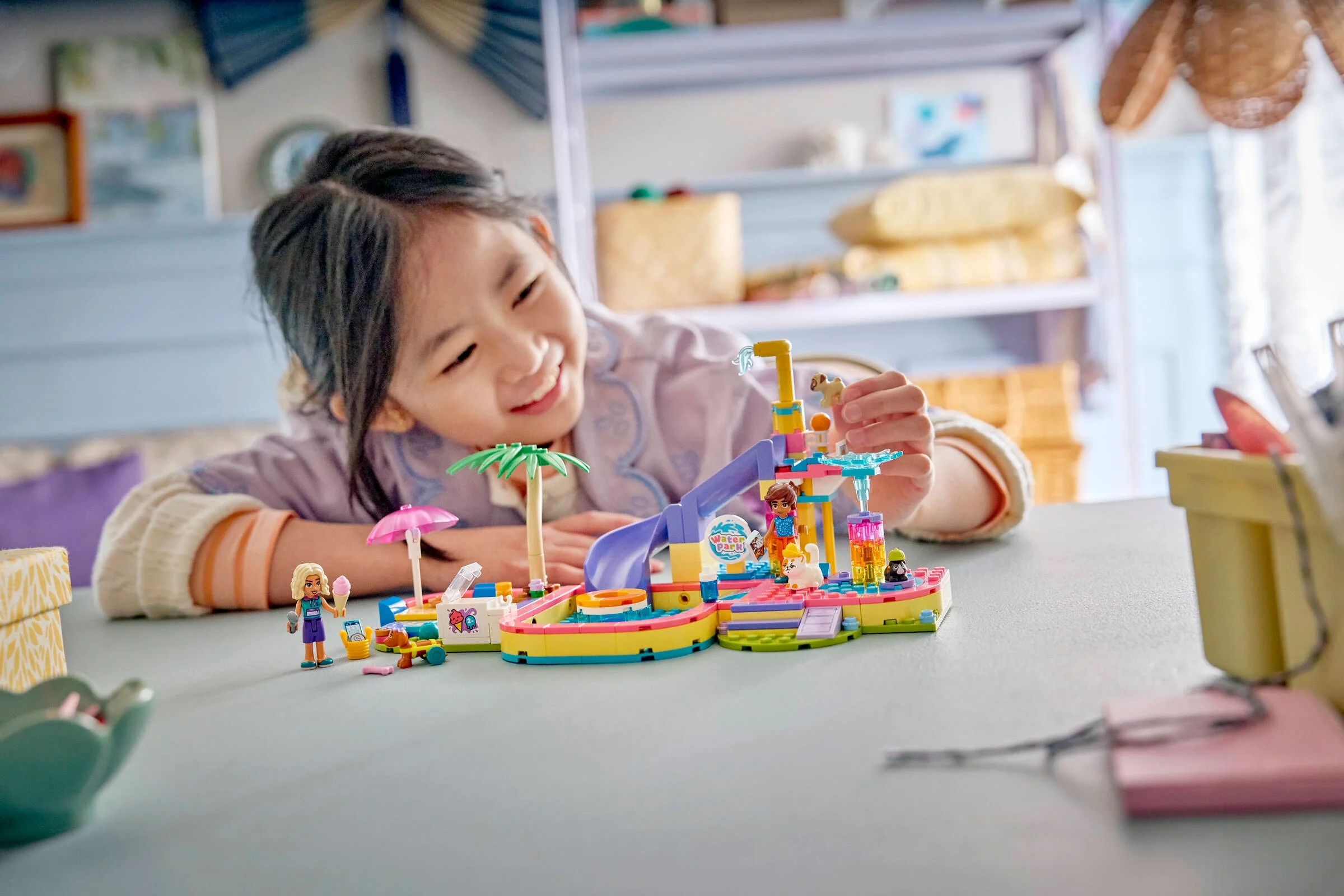 Fetiță zâmbitoare se joacă cu setul LEGO® Friends „Zi de distracție la parcul acvatic”.
