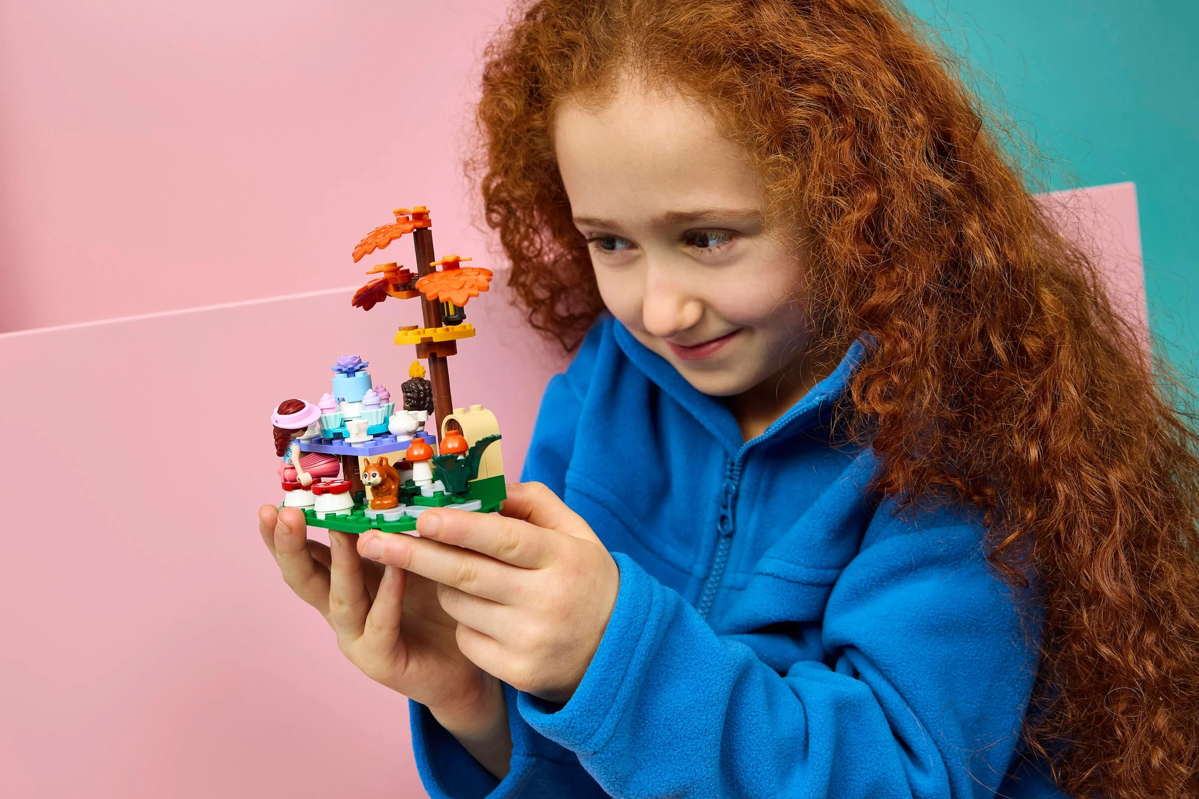 Fetiță admirând setul LEGO Friends „Petrecere în pădure”. Model detaliat cu accesorii.