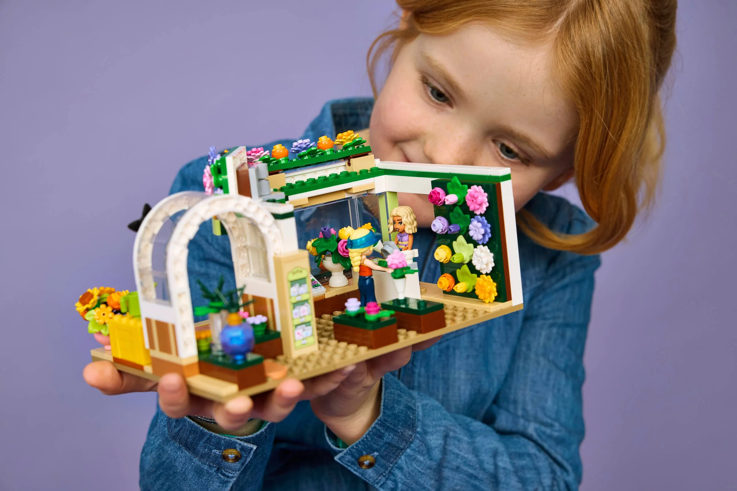 Fetiță admirând magazinul de flori LEGO Friends 42693, o scenă adorabilă.