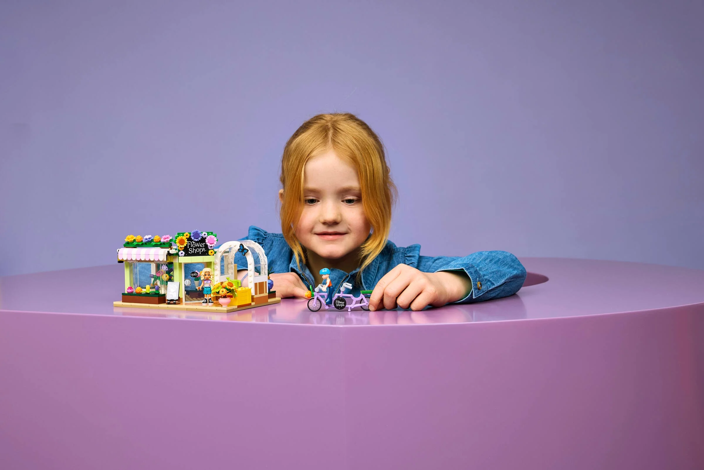 O fetiță se joacă cu florăria LEGO Friends, construind cu pasiune setul.