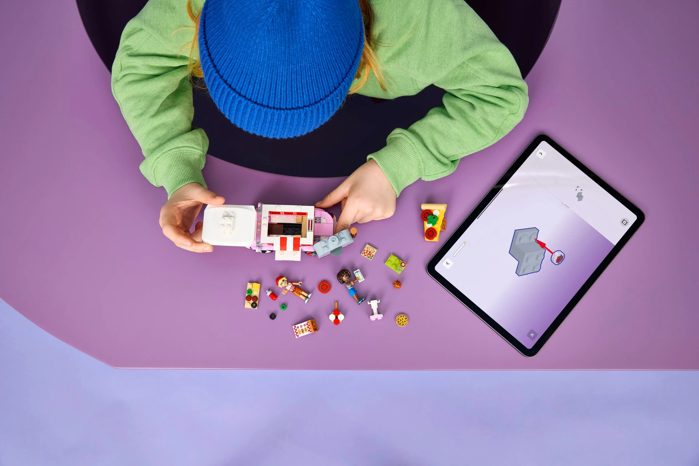 Copil construind camioneta de pizza LEGO Friends 42694, urmând instrucțiunile pe tabletă.