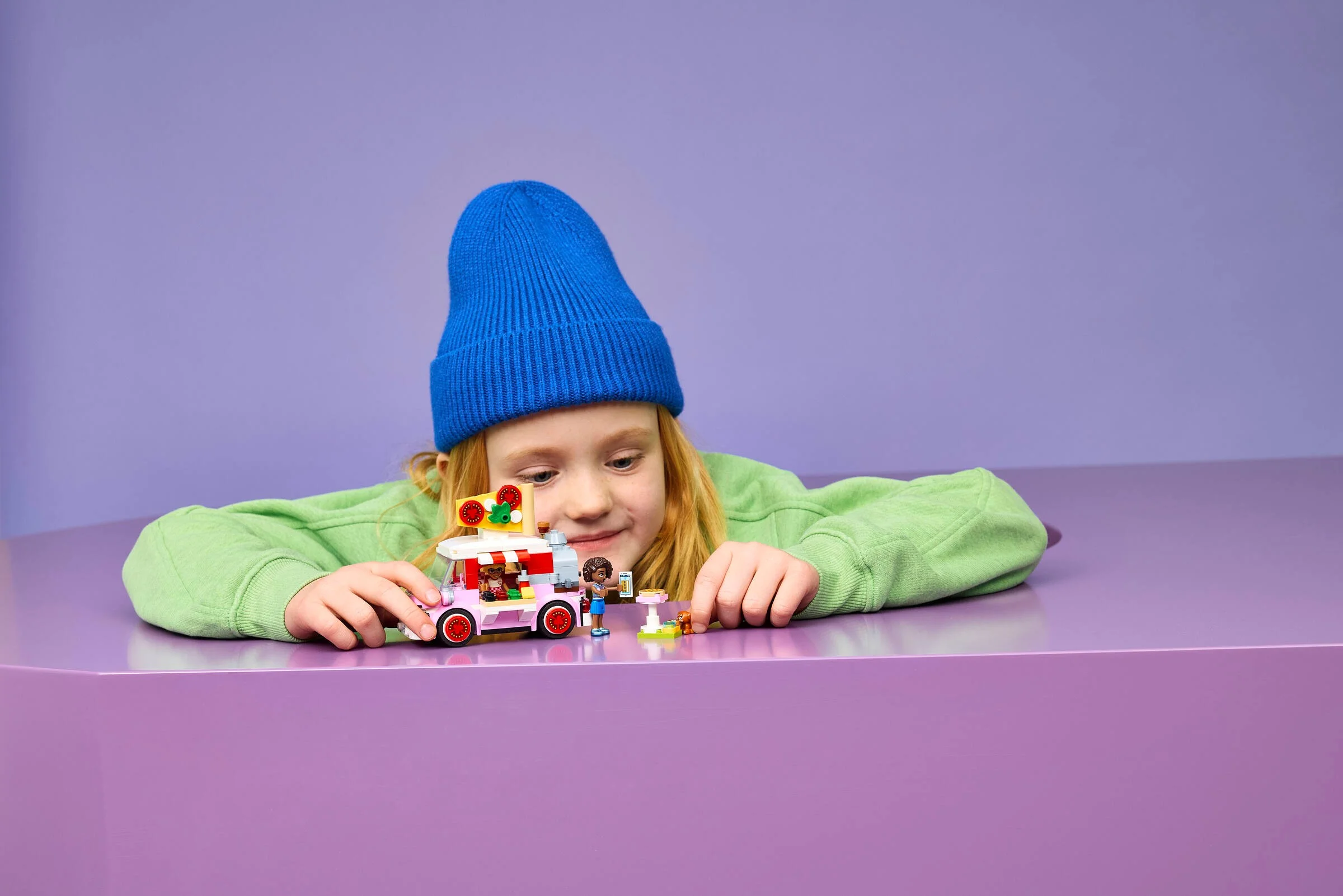 O fetiță se joacă cu camionul de pizza LEGO Friends. Își imaginează povești delicioase.