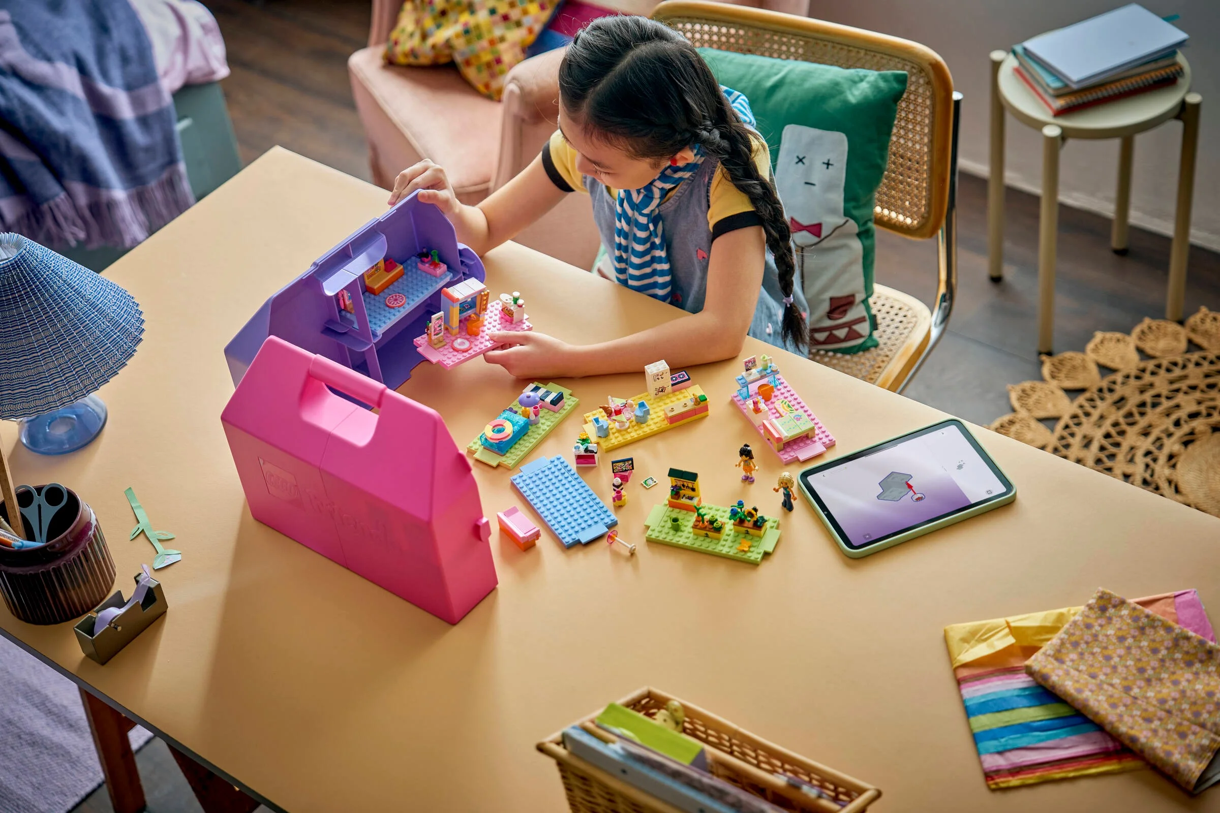 Fetiță construind setul LEGO Friends 42697 cu o valiză transformabilă într-o casă de păpuși.