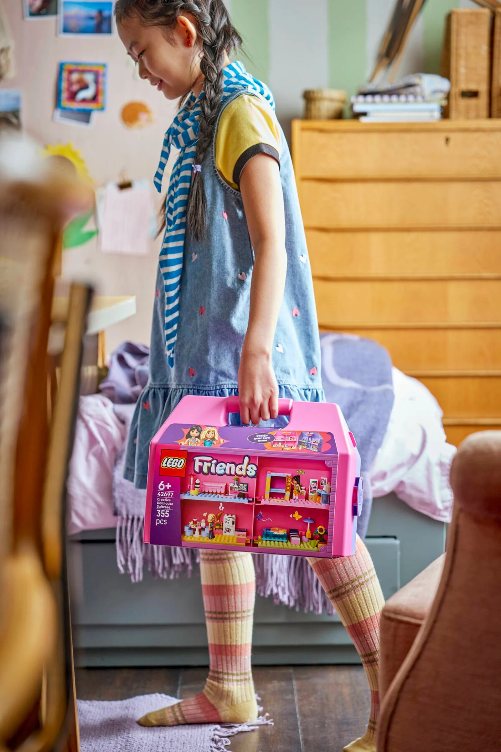 O fetiță ține în mână cutia LEGO Friends 42697, cu o imagine a casei de păpuși.