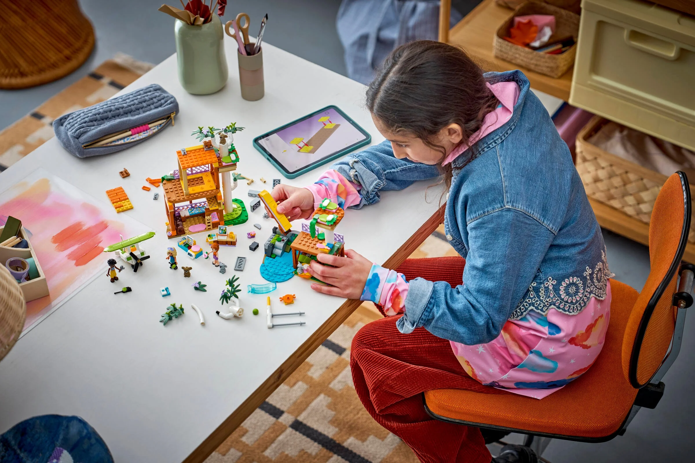 Copil construind setul LEGO 42701, Centru de Îngrijire Koala. Un model în construcție pe masă.