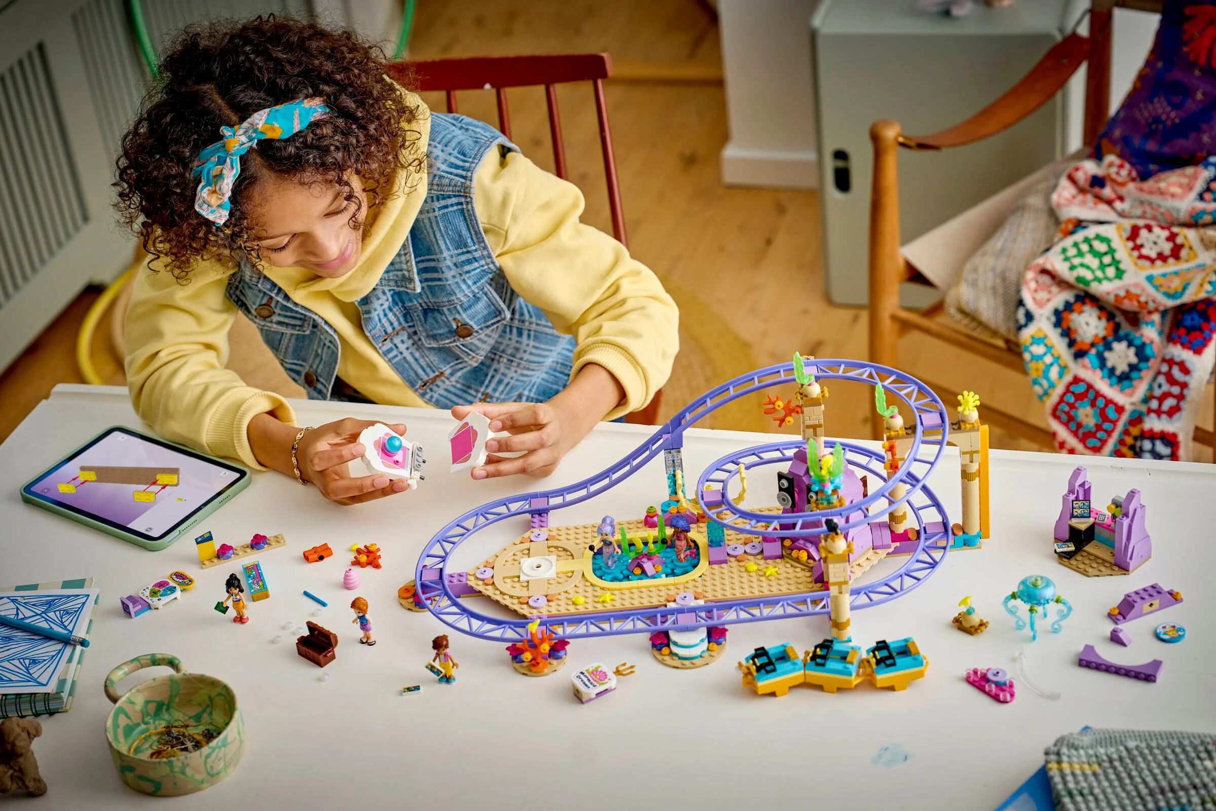 Fată construind setul LEGO Friends 42703, Mermaid Roller Coaster Ride, detaliind rollercoasterul și accesoriile.