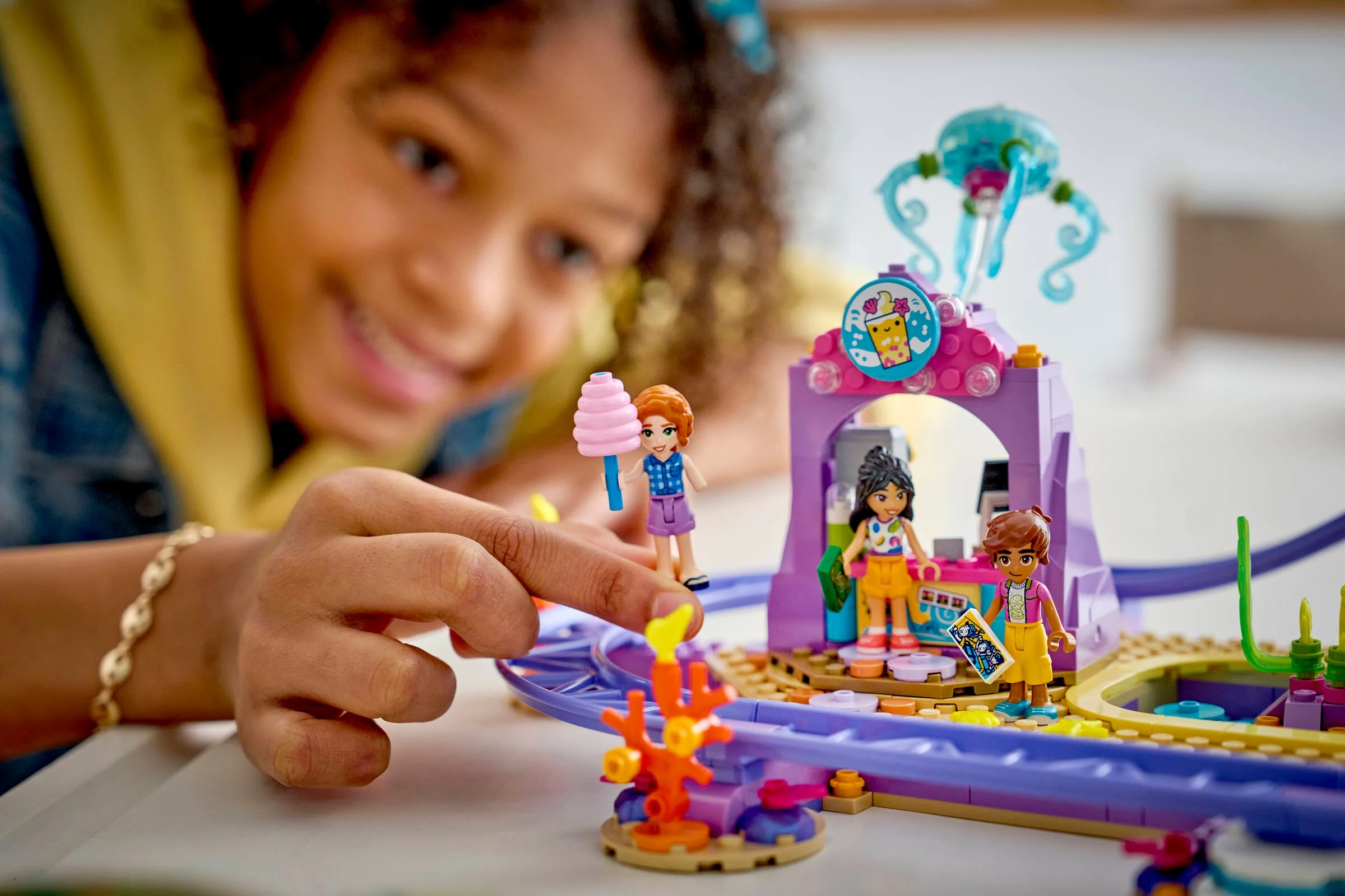 O fată zâmbește în timp ce se joacă cu setul LEGO Friends Montagne Russe Subacvatică.