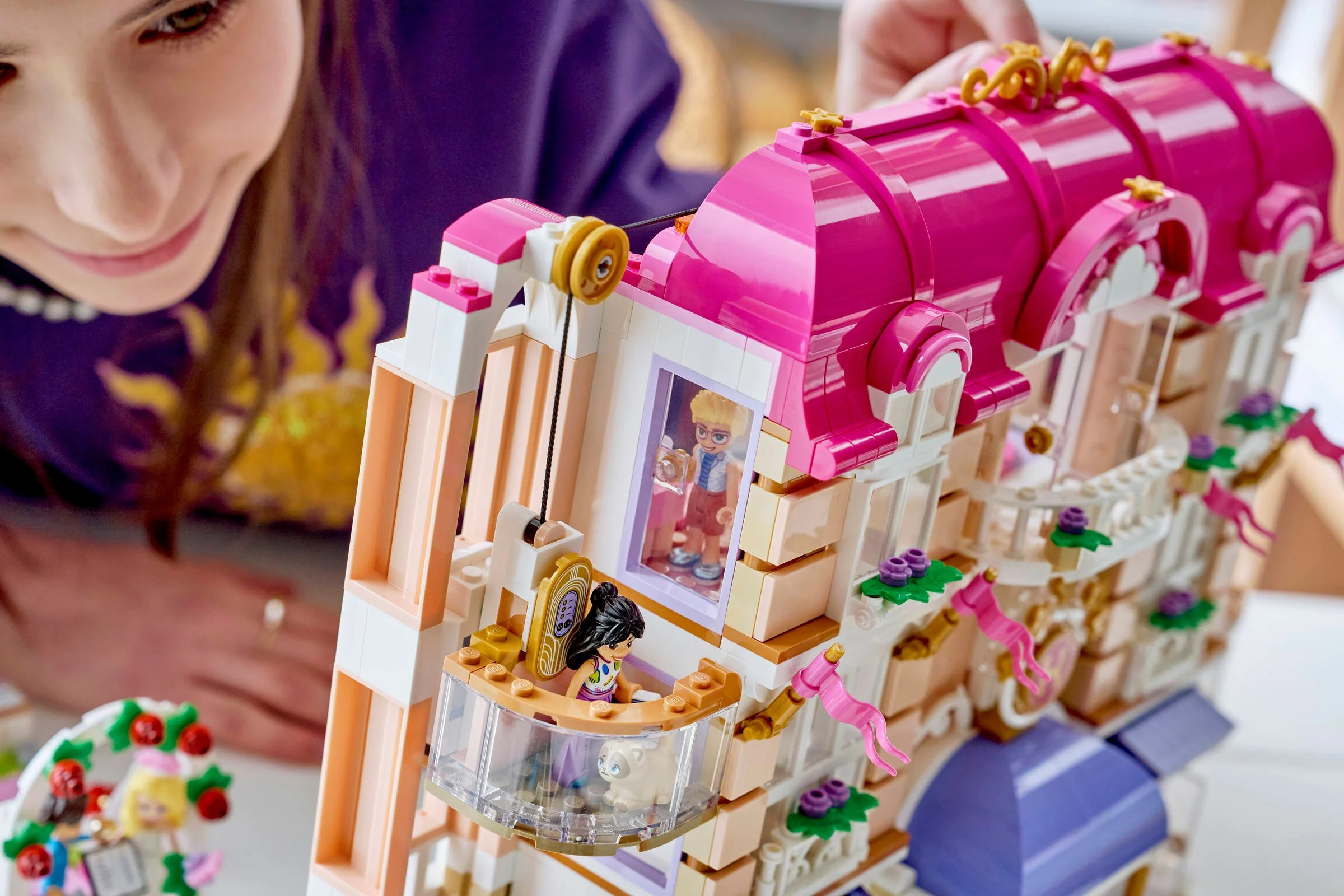 O fată se joacă cu Hotelul Grand din Heartlake City, punând o minifigurină în lift.