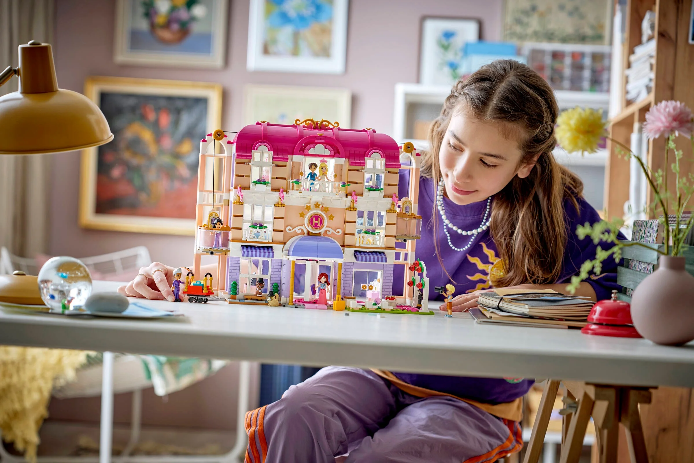 O fetiță se joacă cu setul LEGO Heartlake City Grand Hotel, aranjând minifigurinele.