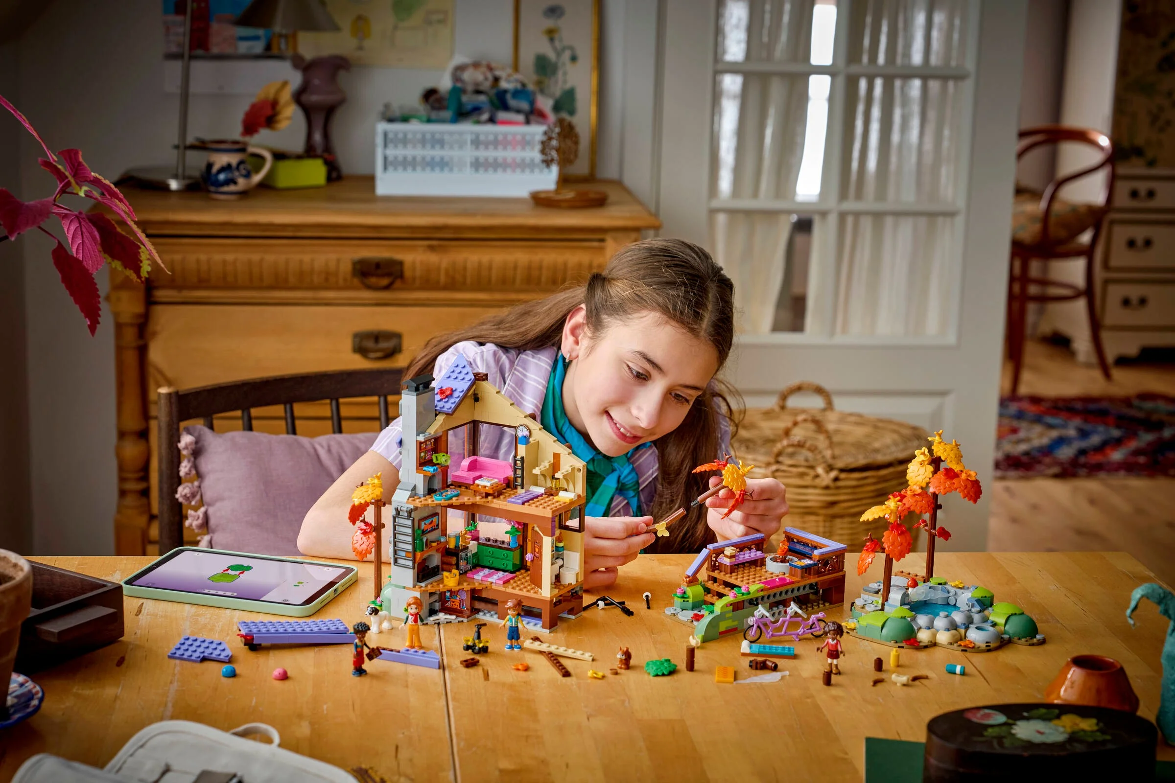 O fată construiește cabana LEGO 42705 într-o cameră luminoasă, toamnă. Atmosferă caldă și primitoare.