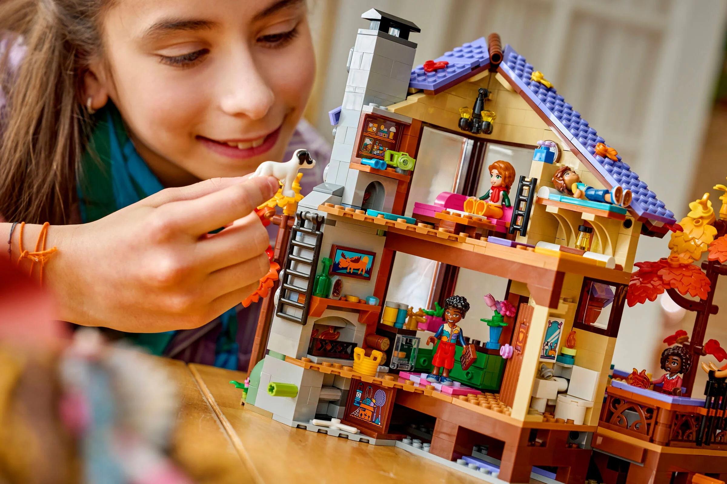 O fată se joacă cu cabana LEGO, explorând detaliile și personajele toamnei. Atmosferă prietenoasă.