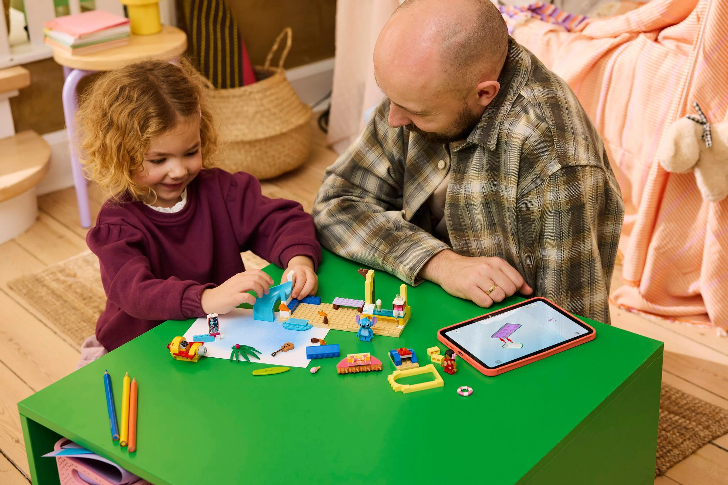 Fetiță și adult construind setul LEGO Plajă cu Lilo & Stitch, distrându-se împreună.