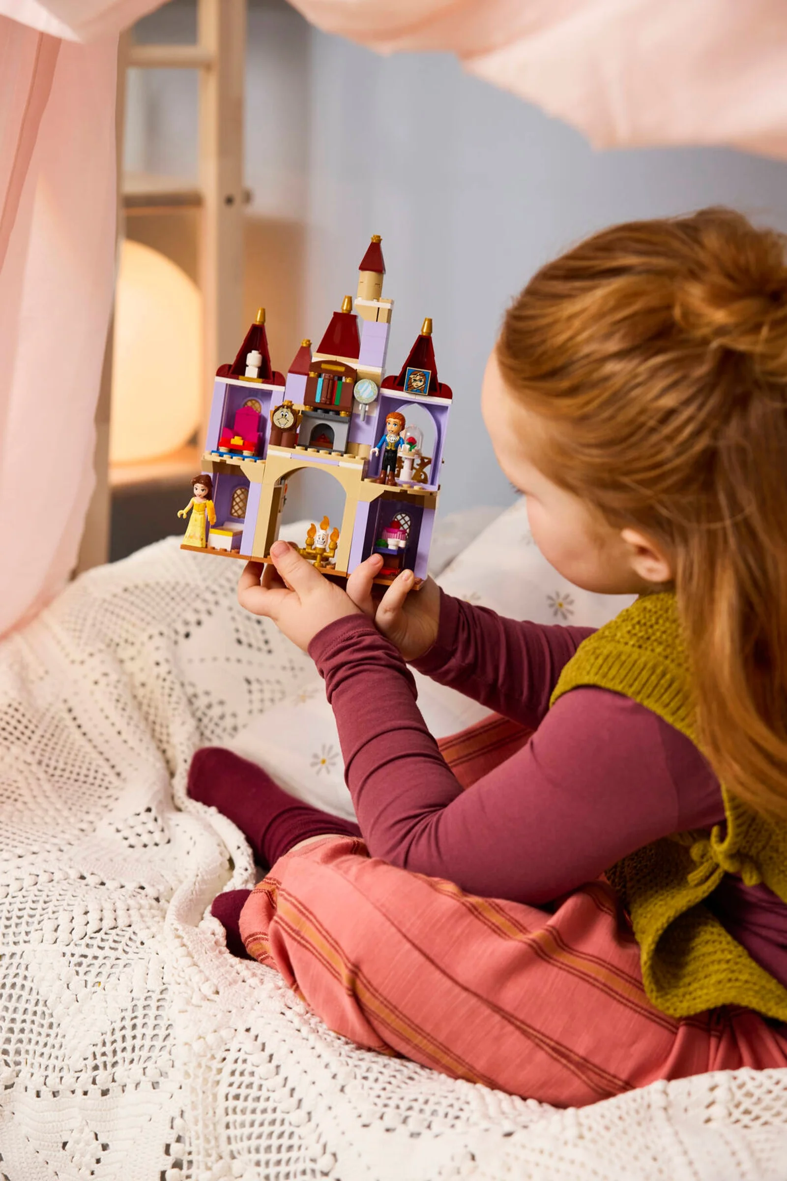 O fată se joacă cu castelul LEGO Frumoasa și Bestia, într-o cameră decorată.