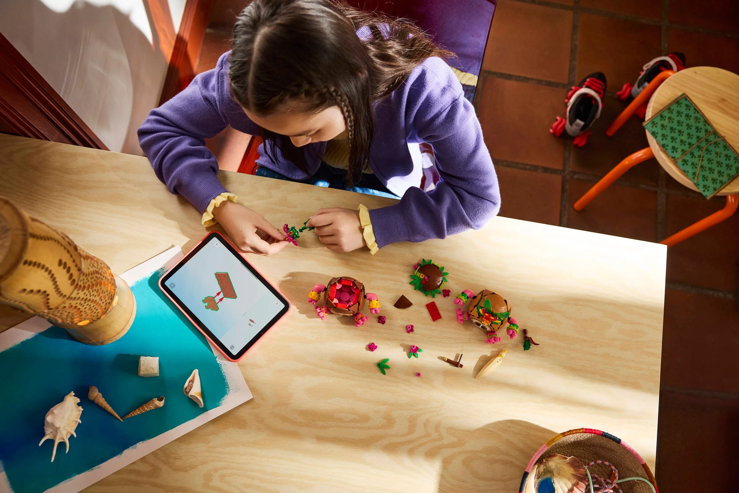 Fetiță construind setul LEGO Kakamora, urmând instrucțiuni pe tabletă. Distracție creativă!