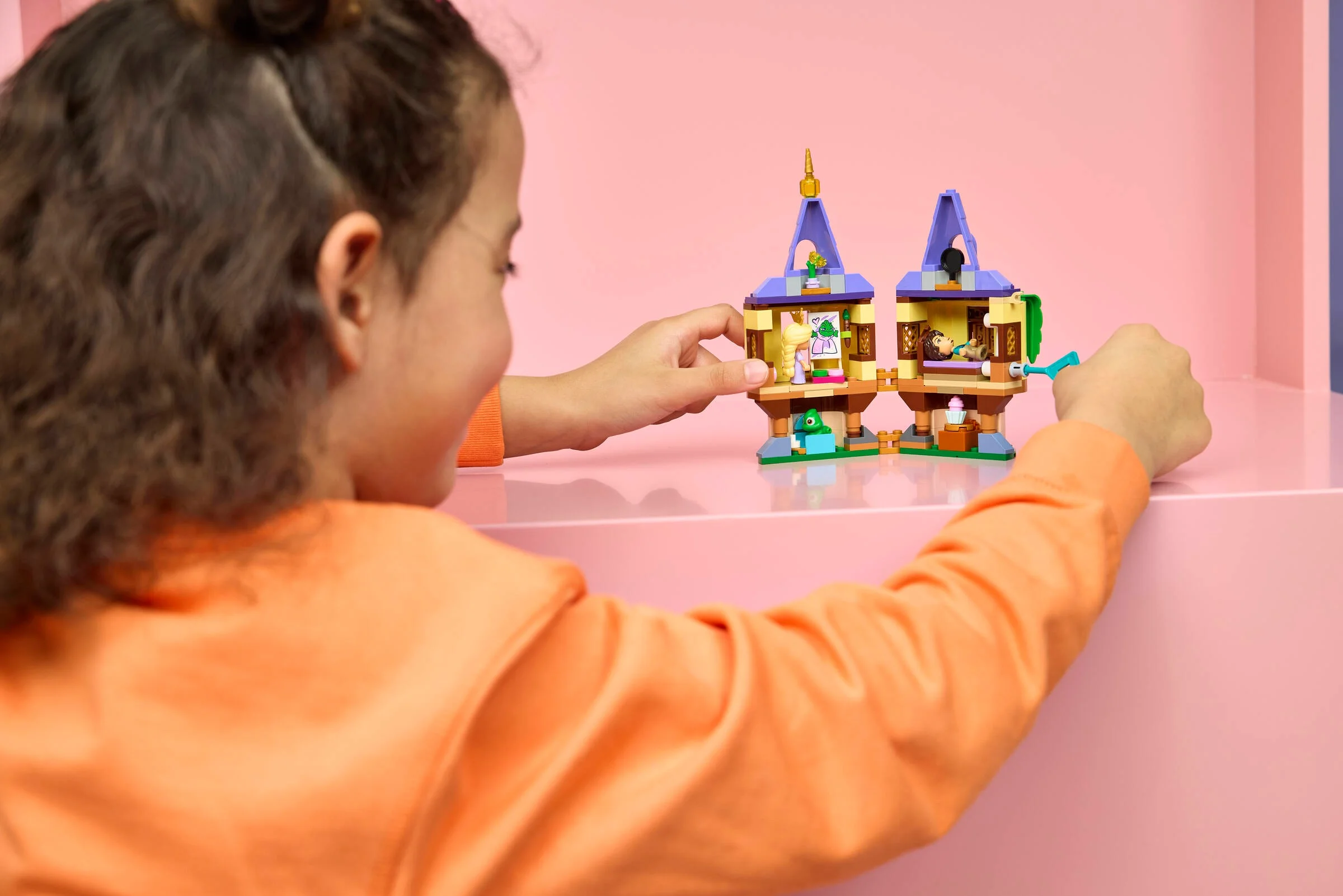 Copil se joacă cu turnul LEGO Rapunzel, setul 43294. Modelul este deschis, cu detalii vizibile.