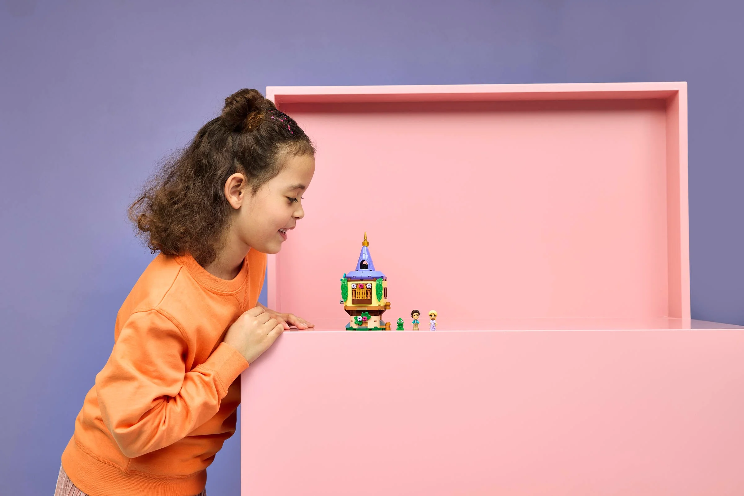 Fată admirând turnul LEGO Rapunzel, mic și colorat. O jucărie încântătoare!