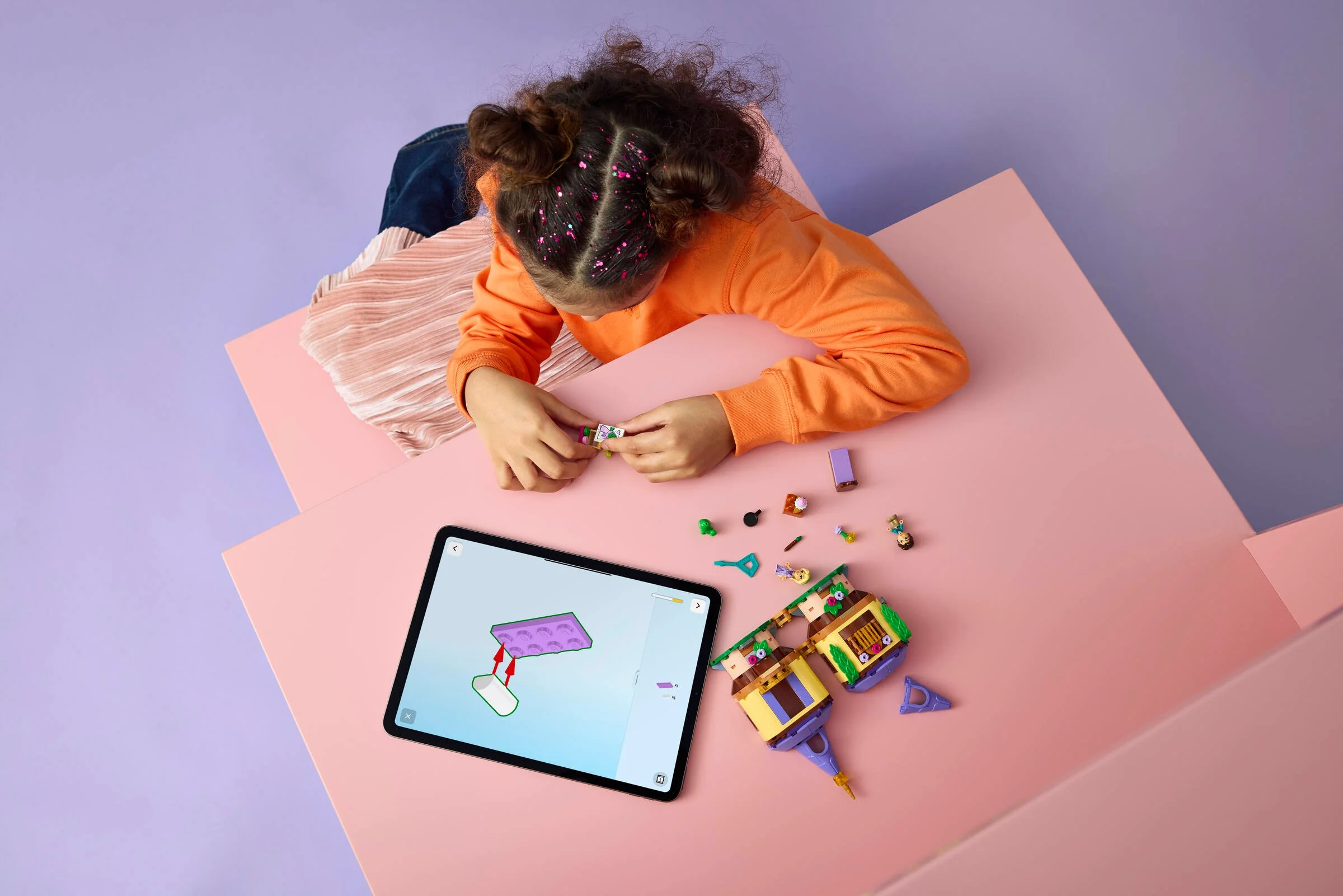 Fetiță construind Turnul lui Rapunzel cu instrucțiuni digitale, folosind o tabletă.